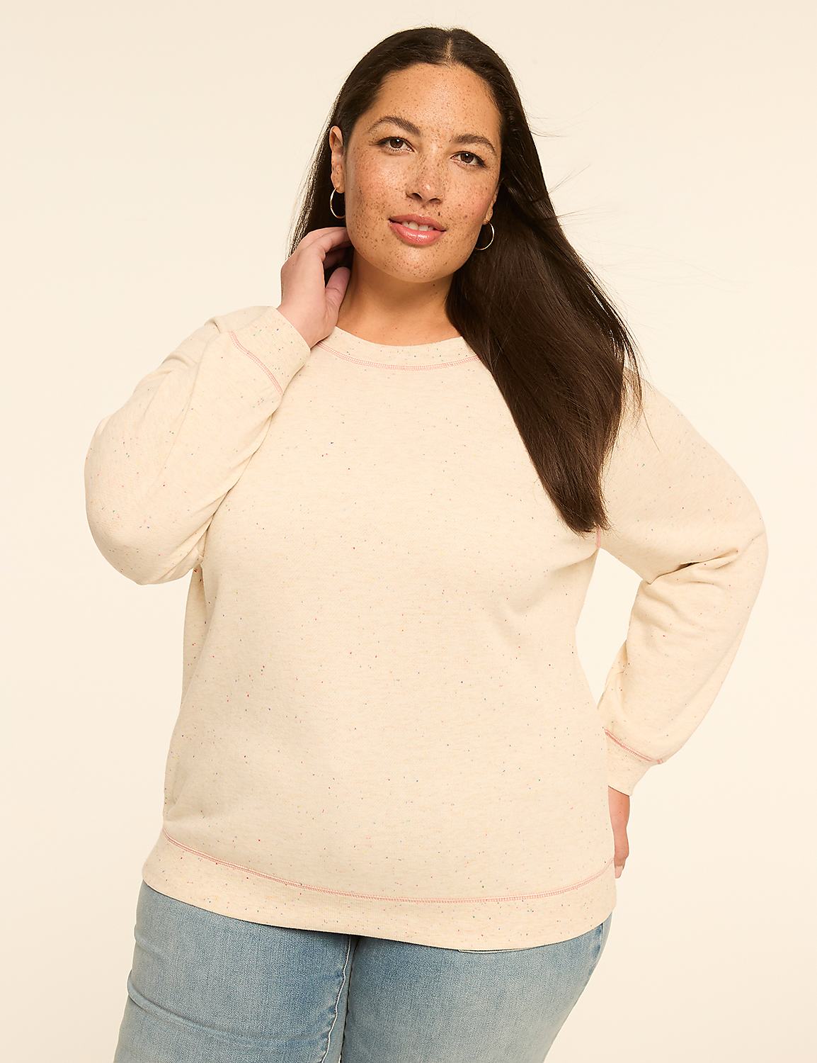 A woman in a cream-colored sweatshirt and blue jeans poses against a plain, light-colored background. Product Image 1