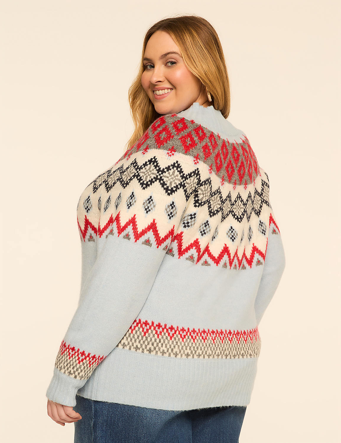 A woman in a light blue sweater with a fair isle pattern smiles over her shoulder against a plain, light-colored background. Product Image 2