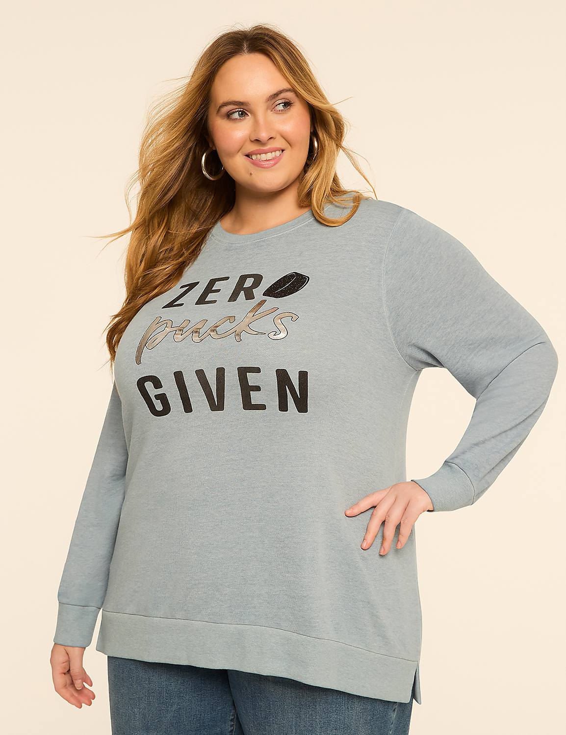 A smiling woman in a light blue sweatshirt with "ZERO PUCKS GIVEN" printed on it stands against a plain, light-colored background. Product Image 1