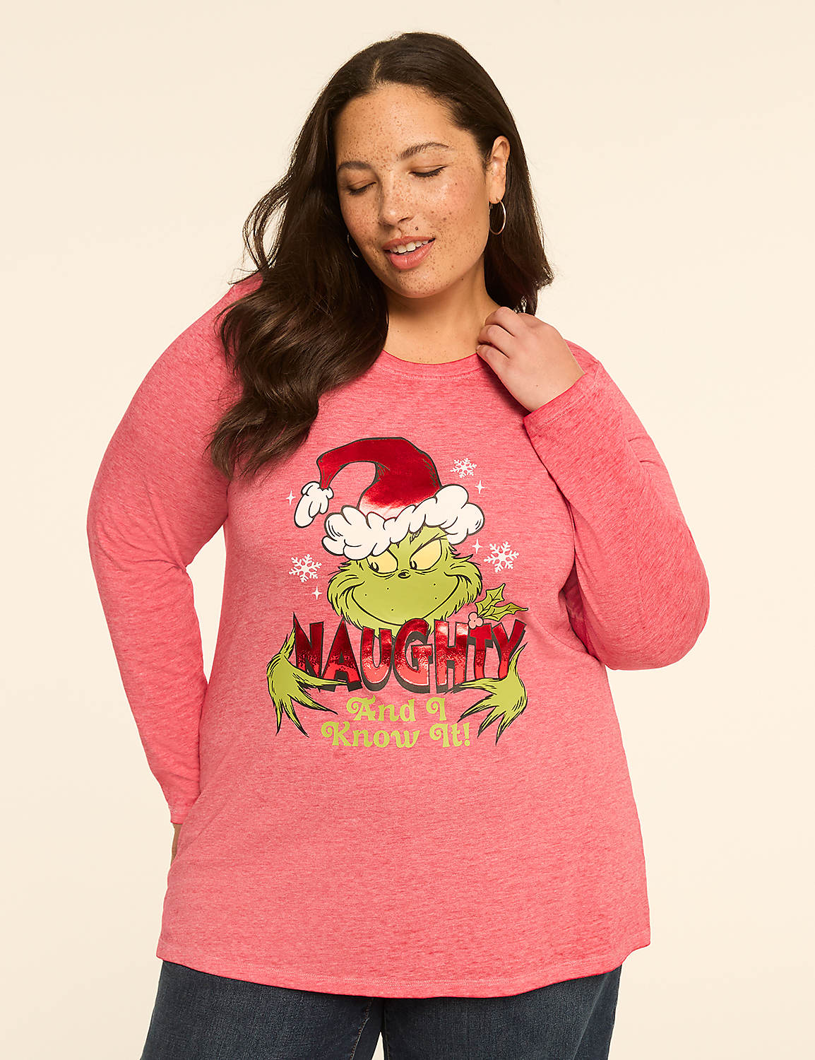 A woman in a pink long-sleeved shirt with a Grinch graphic stands against a plain, light-colored background. Product Image 1