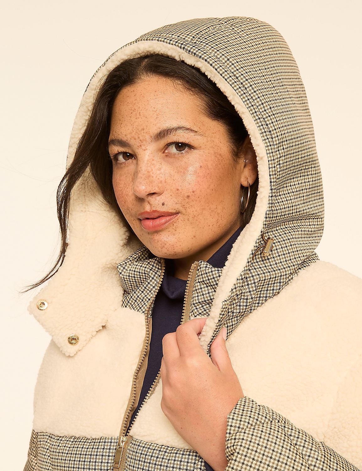 A woman with freckles wears a cream and plaid hooded jacket against a plain, light background. Product Image 4