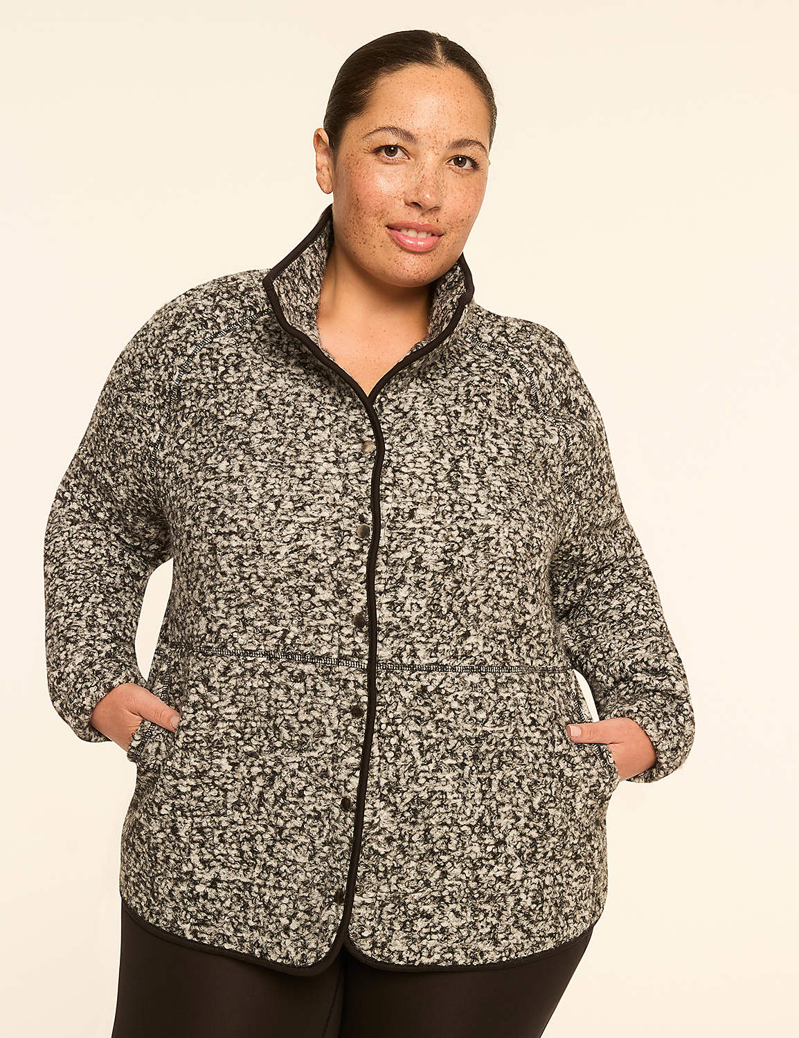 A woman in a speckled jacket with her hands in her pockets stands against a plain, light-colored background. Product Image 1