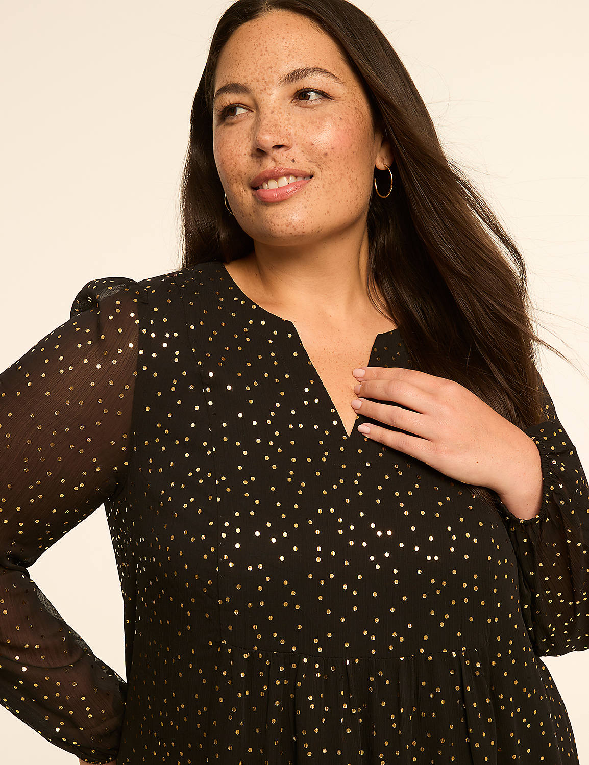 A woman in a black, gold-dotted dress smiles gently, her hand resting on her chest, against a plain, light-colored background. Product Image 3