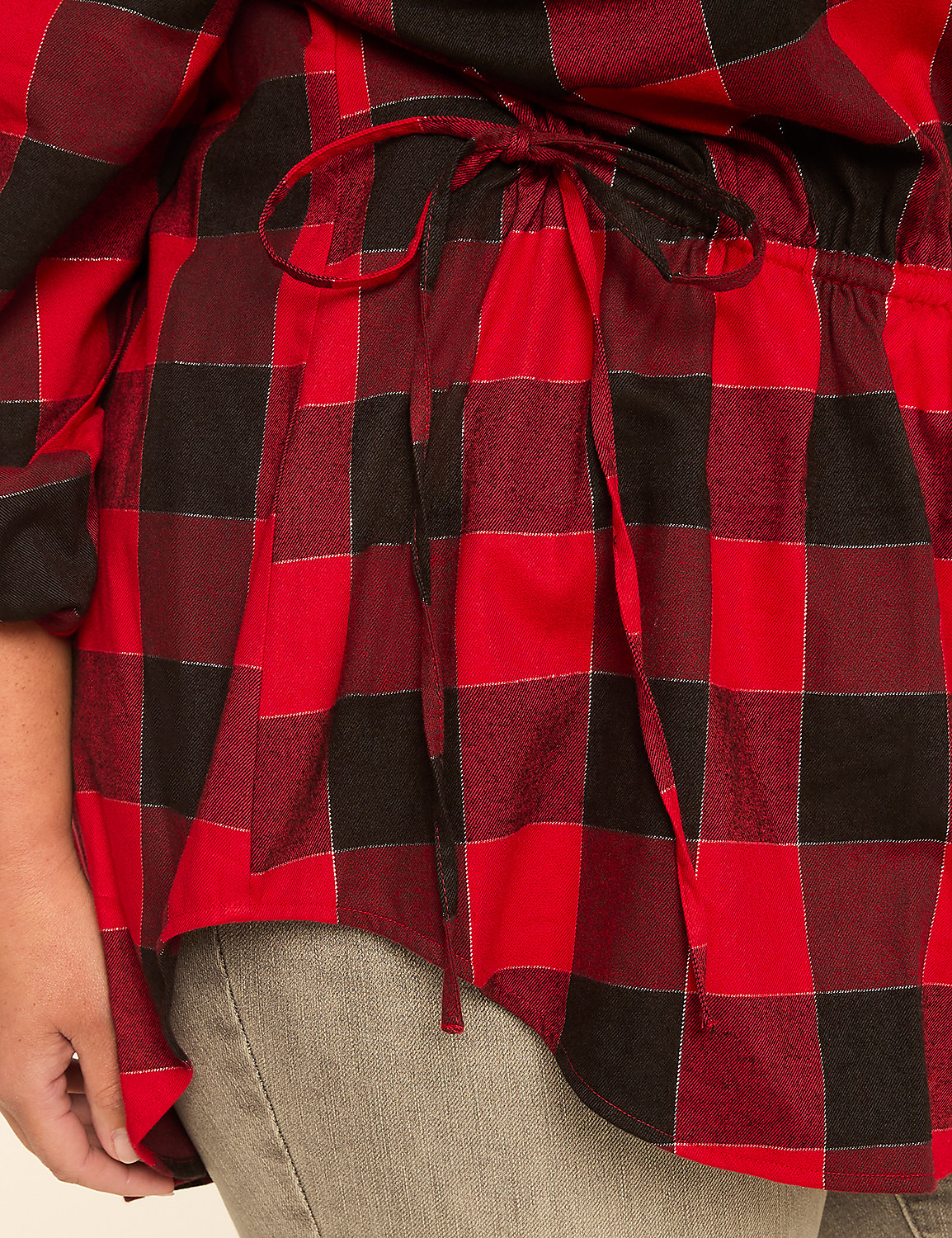 A close-up of a red and black buffalo plaid shirt with a drawstring waist is worn over grey pants. Product Image 4