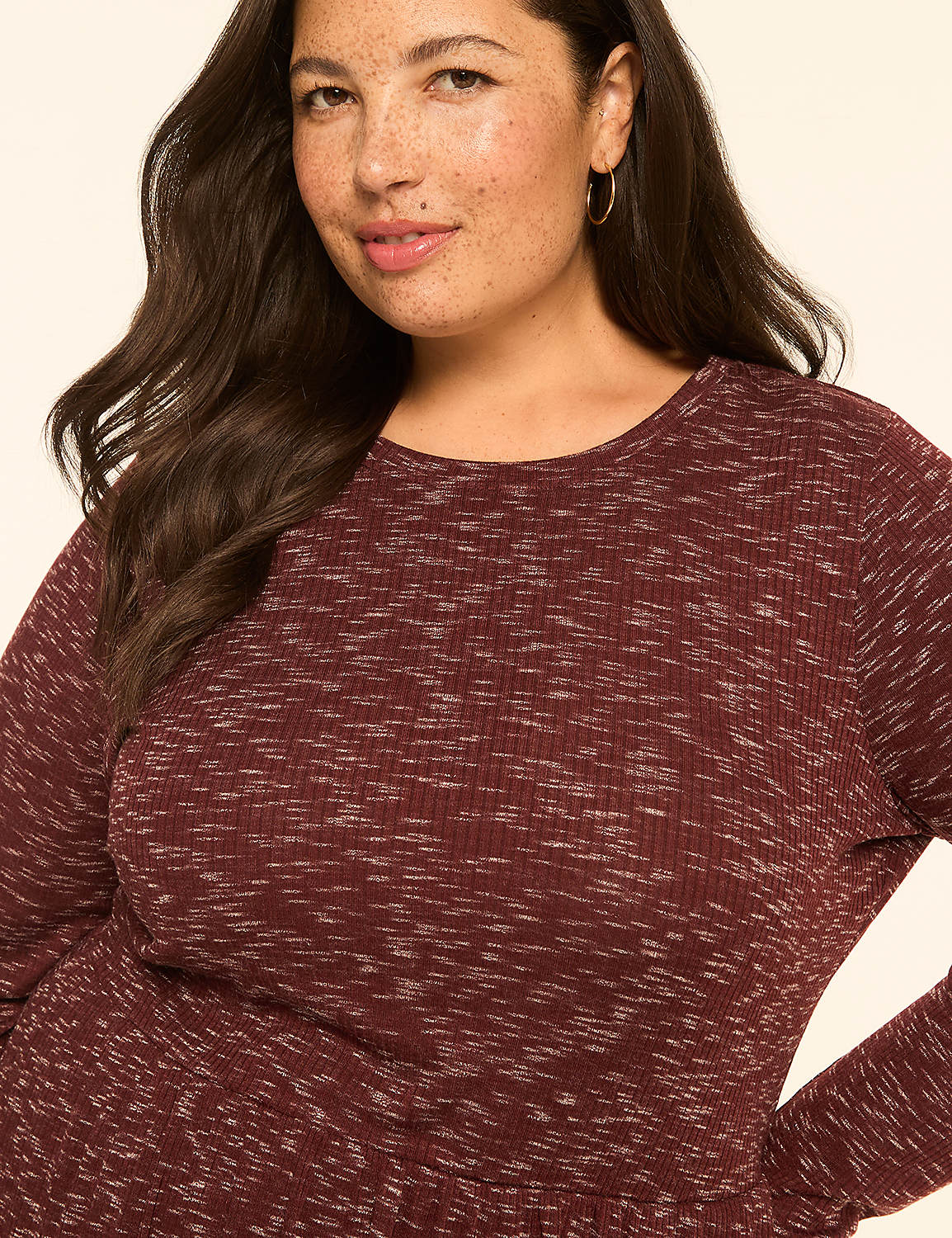 A woman with dark wavy hair and freckles smiles gently in the foreground, wearing a marled burgundy long-sleeved shirt against a plain, light-colored background. Product Image 3