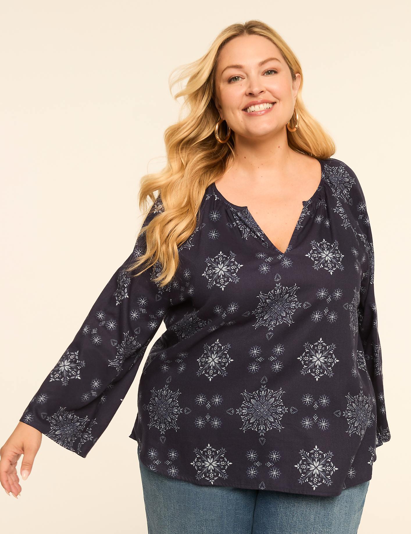 A smiling woman with blonde hair wears a dark blue snowflake-patterned blouse and jeans against a plain, light background. Product Image 1