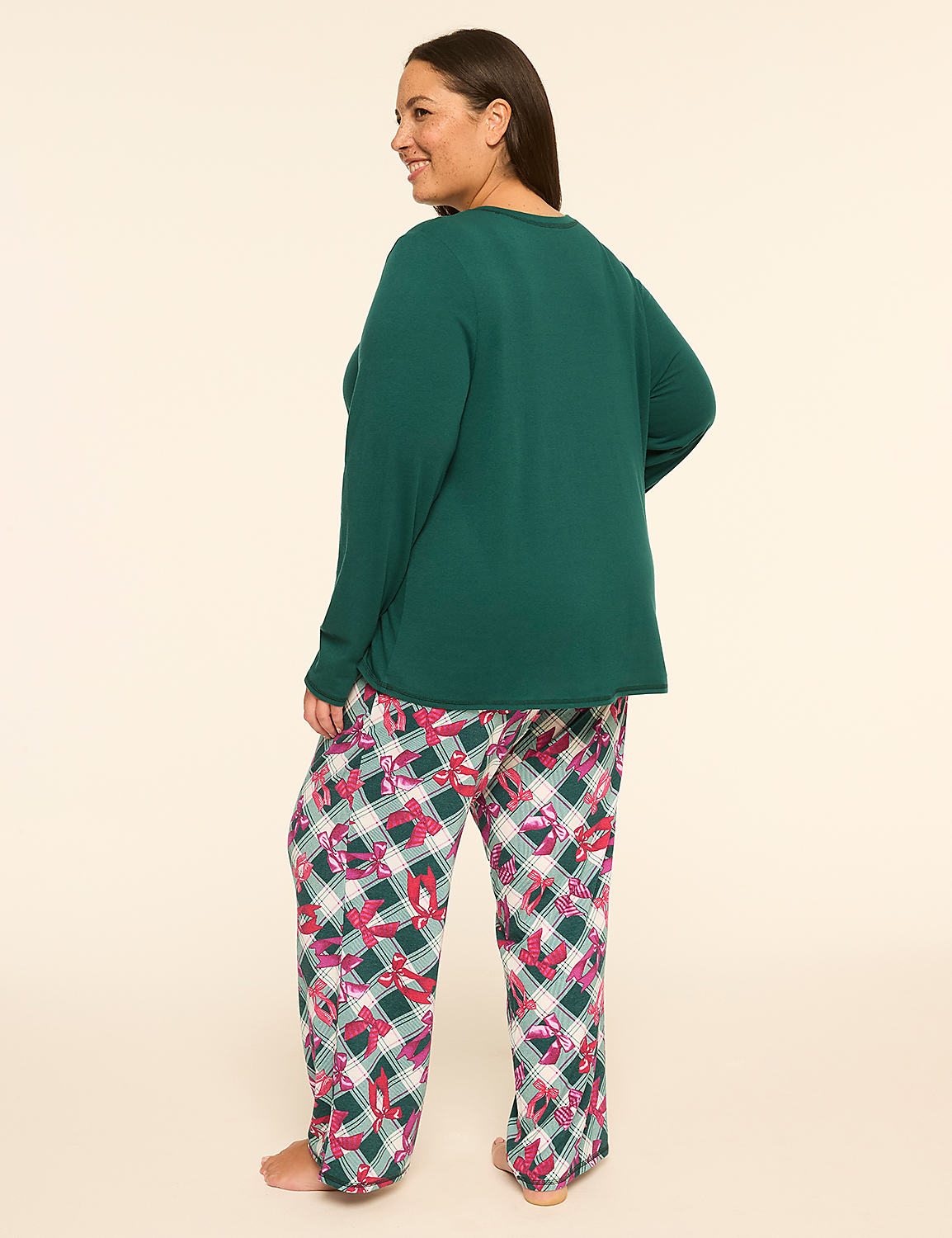 A woman in a green long-sleeved shirt and plaid pajama pants stands against a plain, light-colored background. Product Image 2