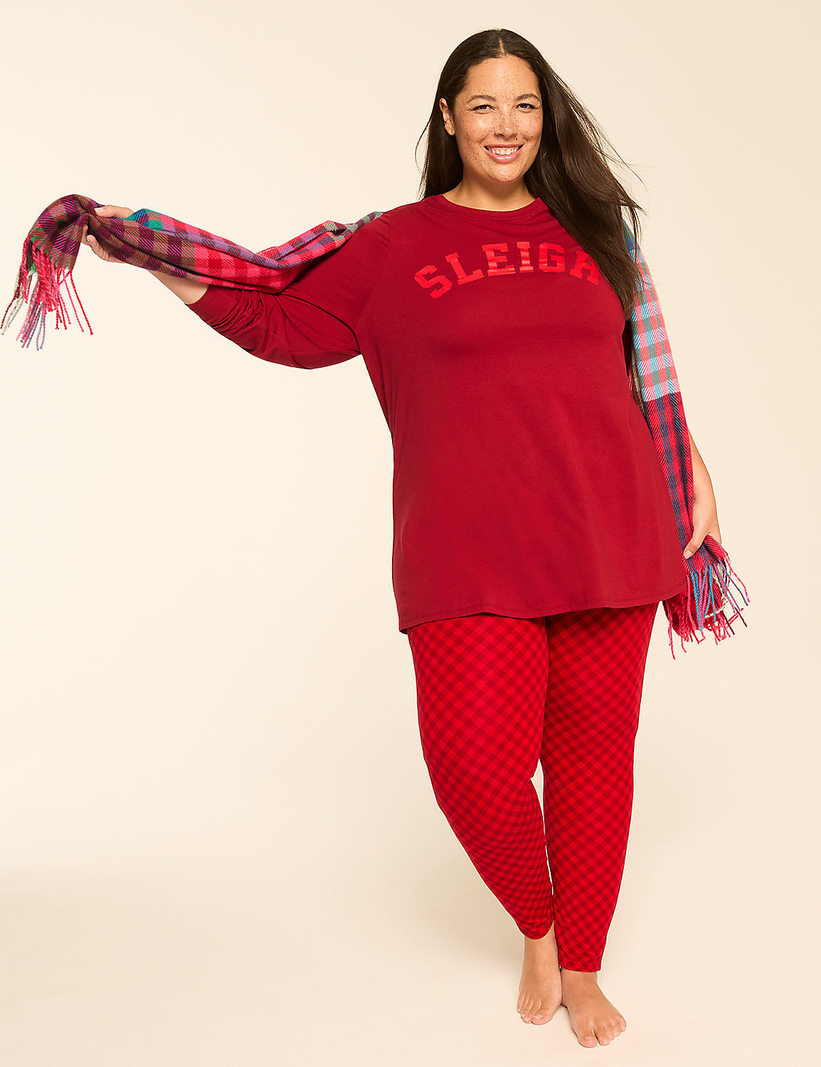 A smiling woman in red pajamas with a plaid scarf stands against a plain, light-colored background. Product Image 1