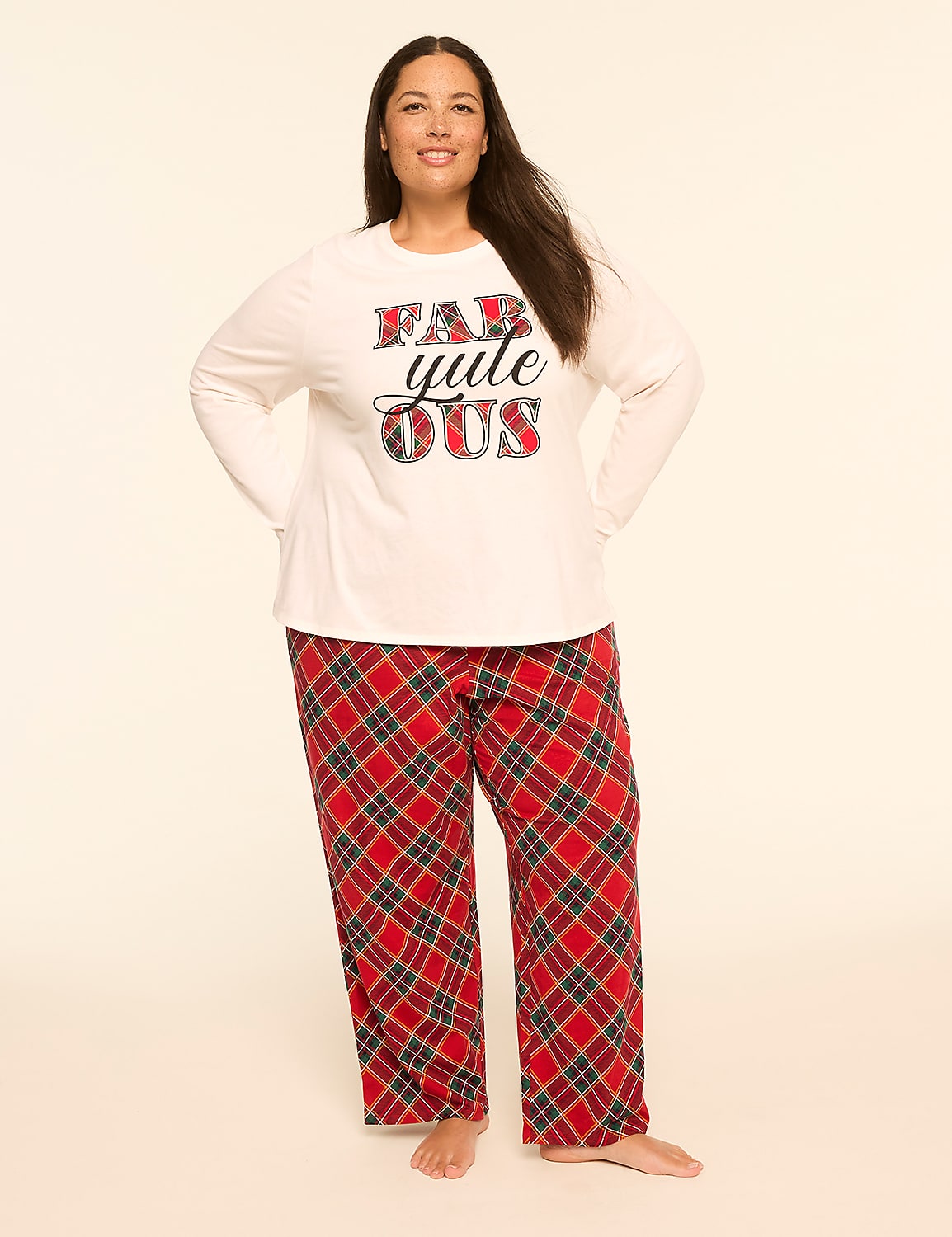 A woman in a white long-sleeved shirt with "Fabulously" printed on it and red plaid pajama pants stands against a plain, light-colored background. Product Image 1