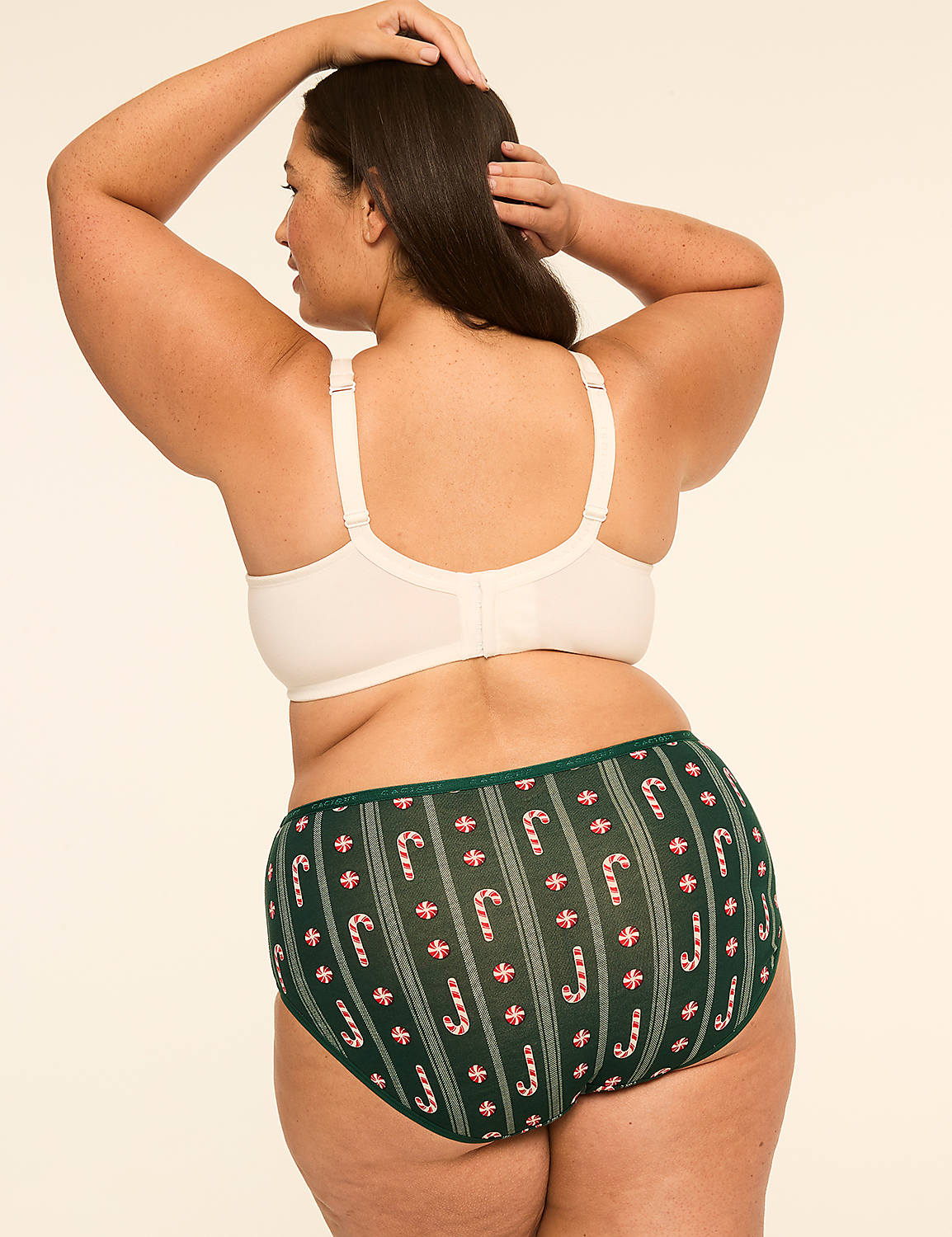 A woman in a cream-colored bra and green candy cane patterned underwear stands against a plain, light background. Product Image 2