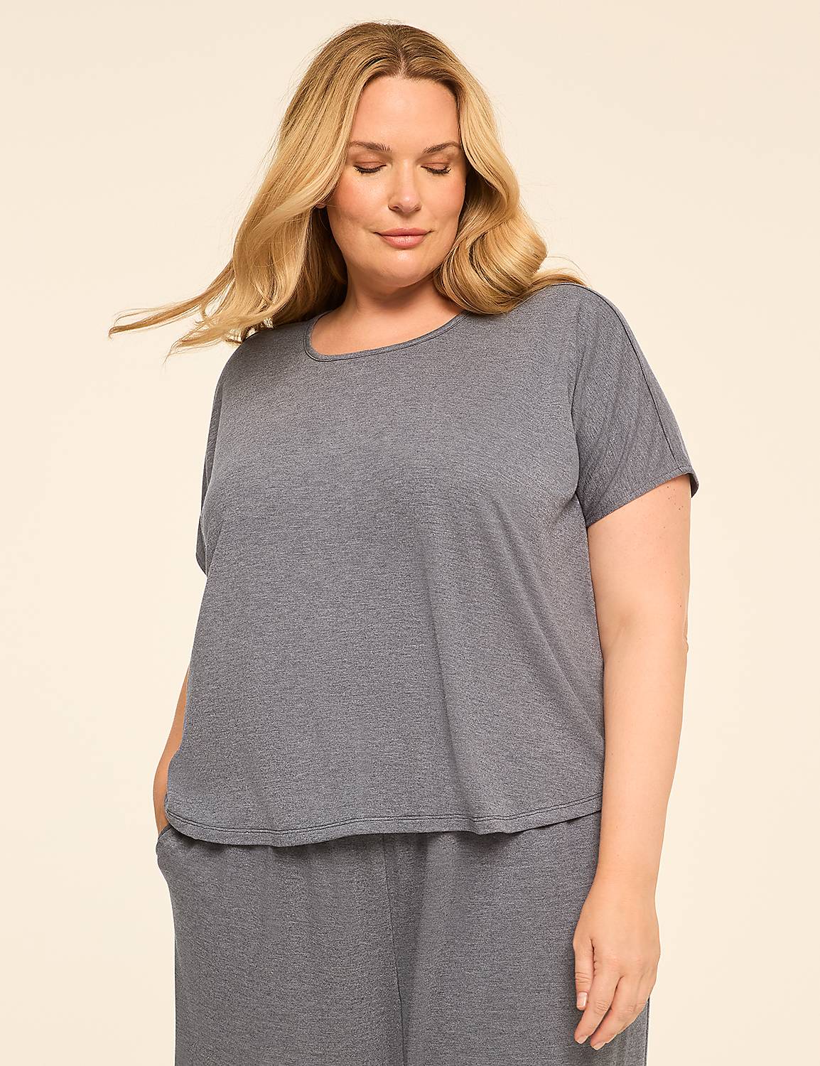 A blonde woman in a grey t-shirt and pants stands against a plain, light-colored background. Product Image 1