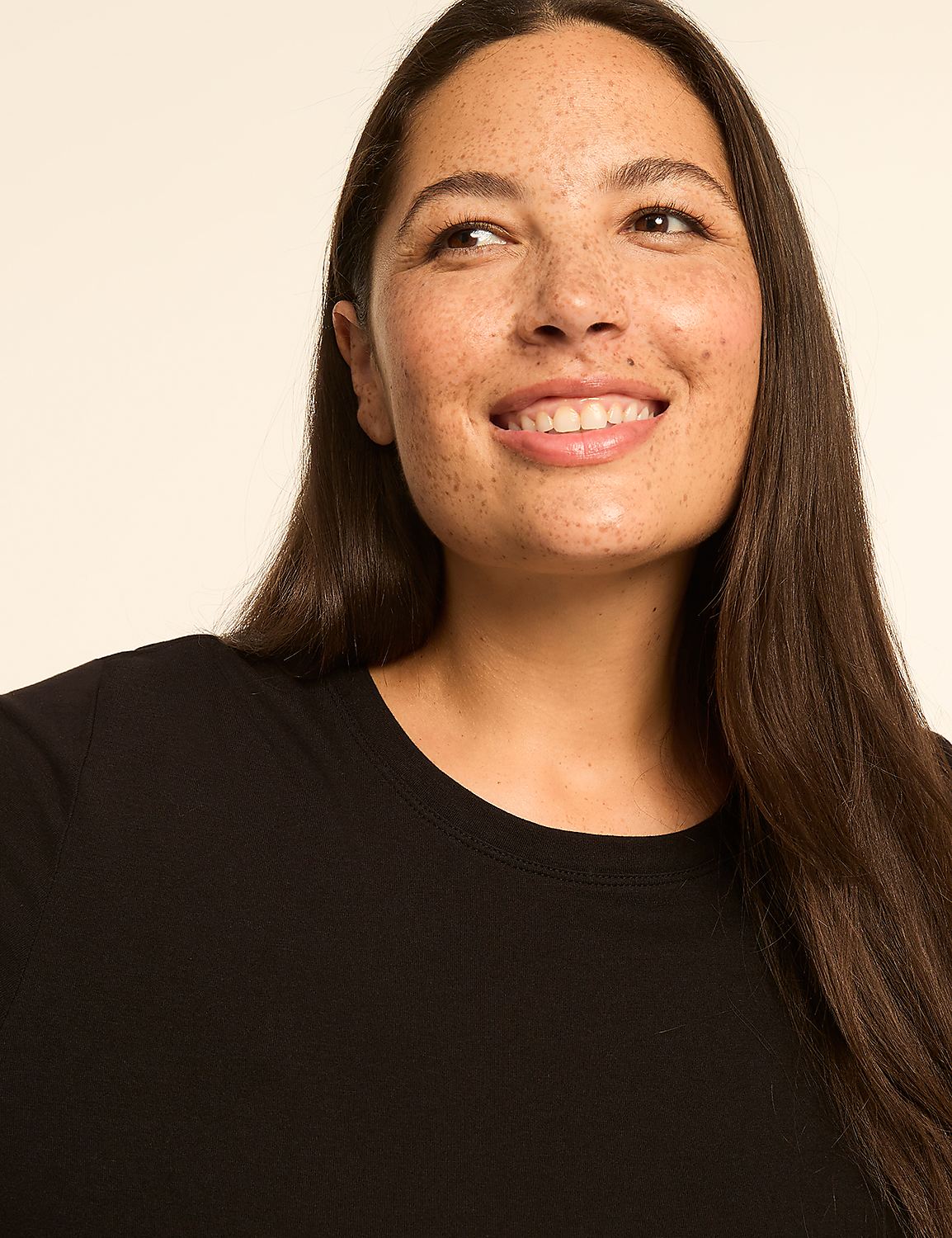 A smiling woman with long dark hair and freckles in a black shirt is set against a plain, light background. Product Image 4