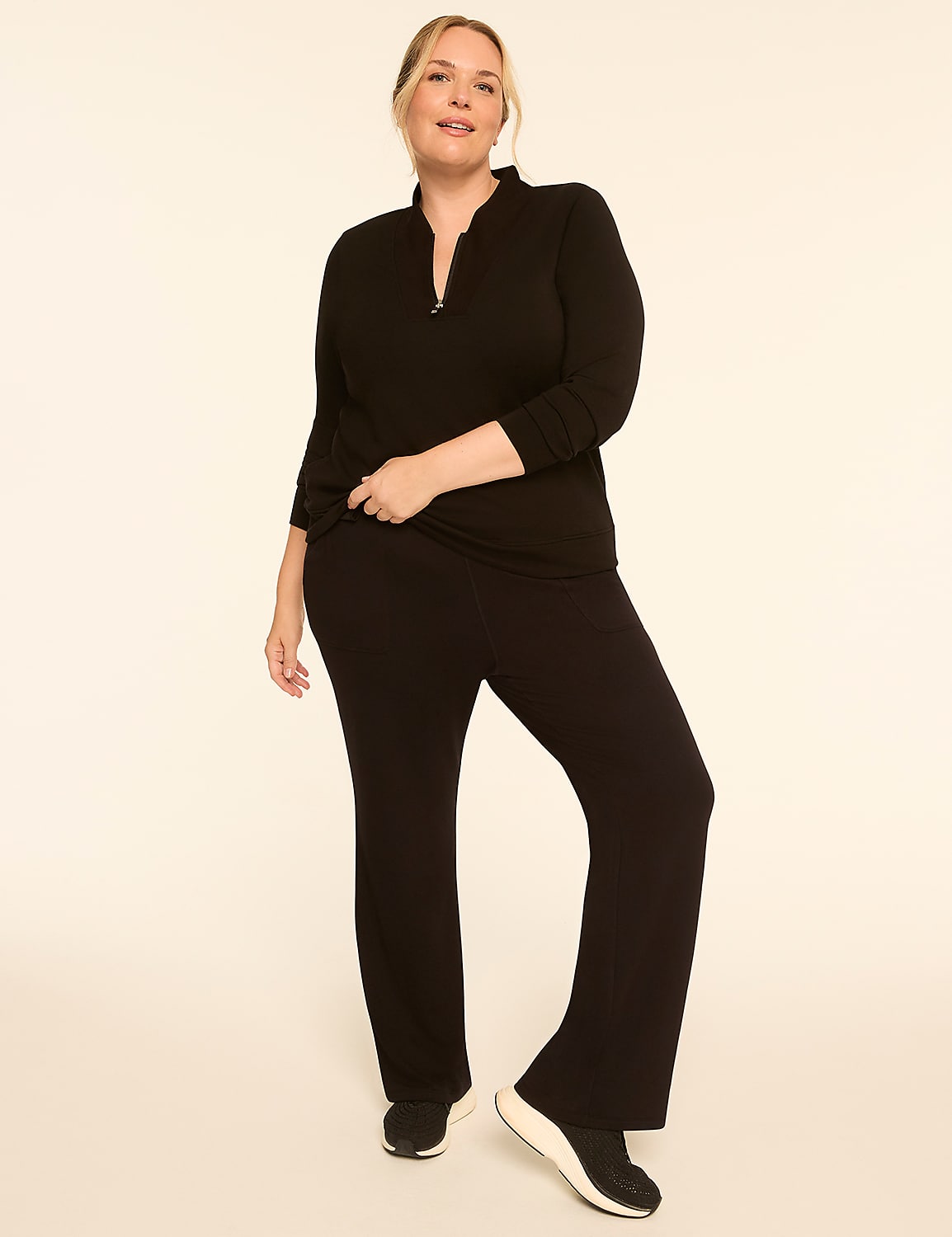 A woman in a black top and pants stands against a plain, light-colored background. Product Image 3