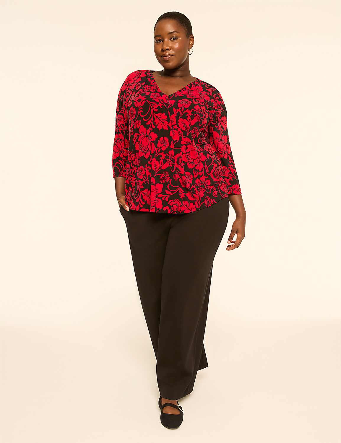 A woman in a red floral top and black pants stands against a plain, light background. Product Image 3