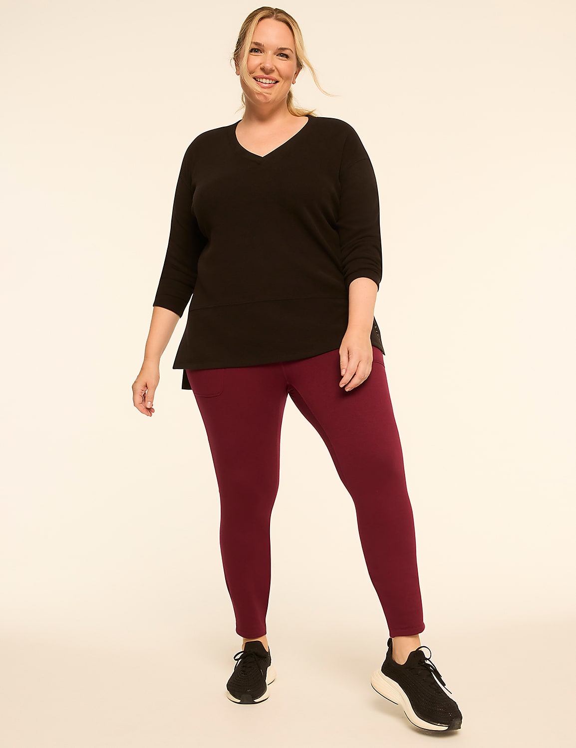 A smiling woman in a black top and burgundy leggings stands against a plain, light-colored background. Product Image 3