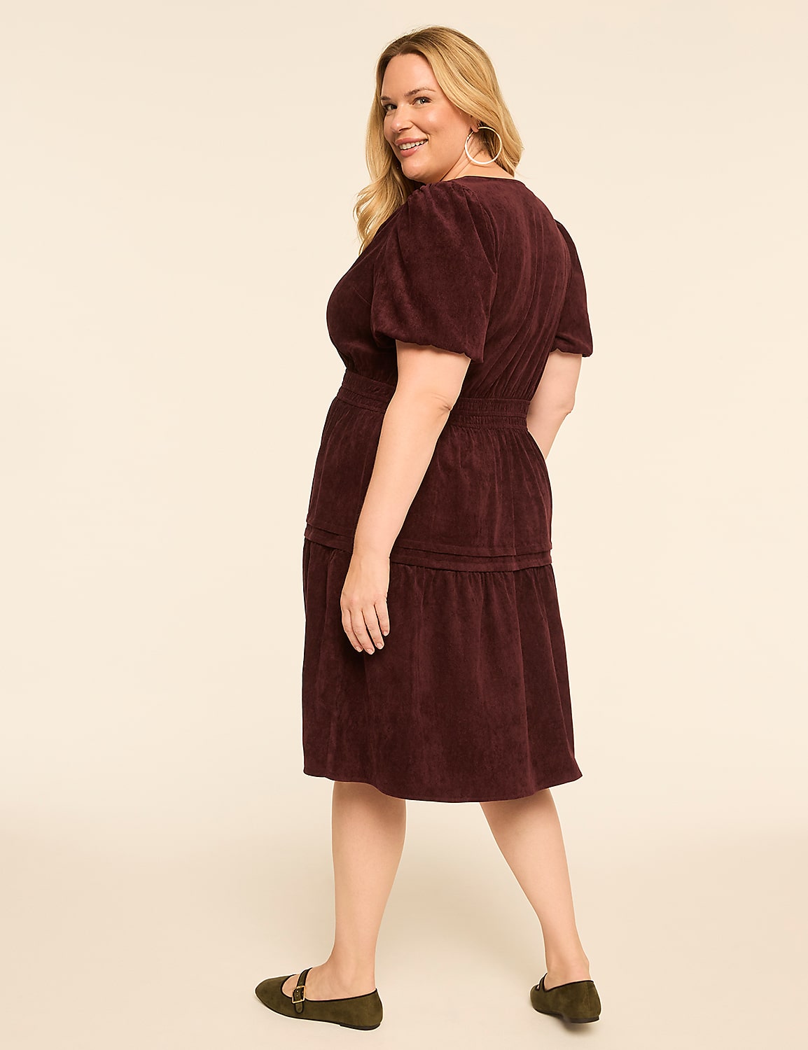 A woman in a burgundy corduroy dress stands against a plain cream background. Product Image 2