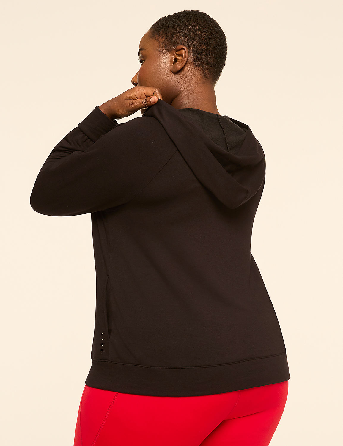 A woman in a black hoodie and red leggings stands against a plain, light-colored background. Product Image 2