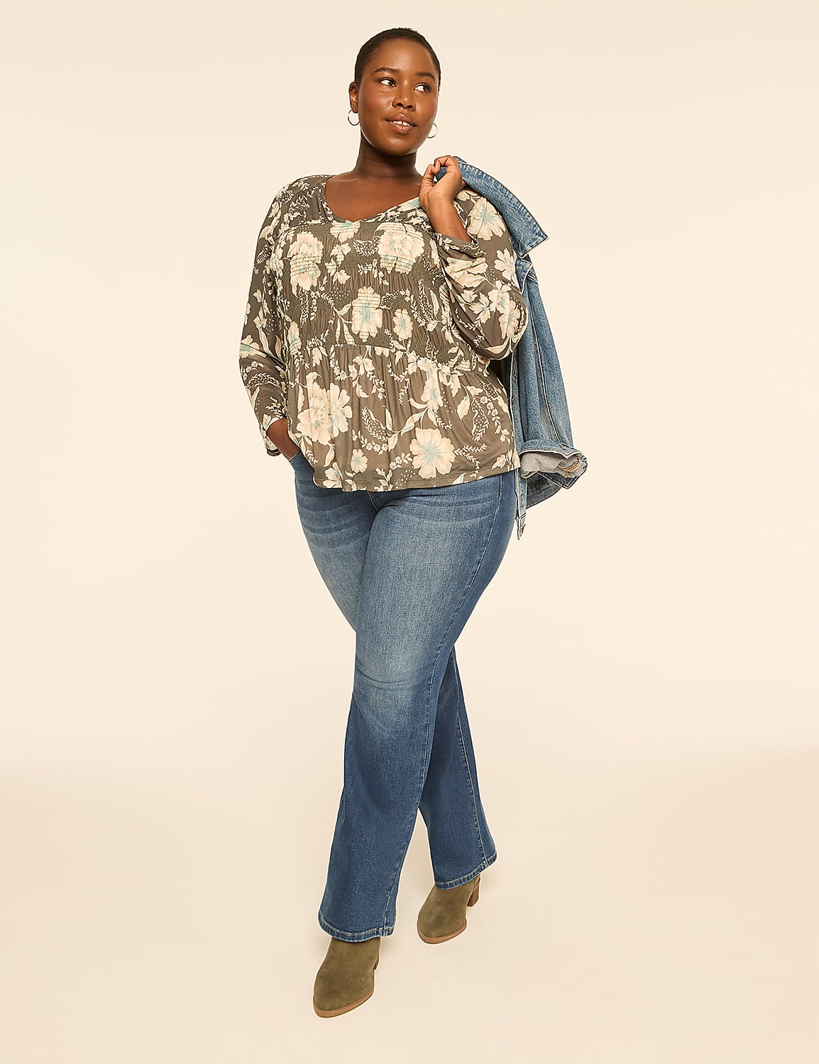 A woman in a floral top and jeans stands against a plain, light-colored background, with a denim jacket draped over her shoulder. Product Image 3