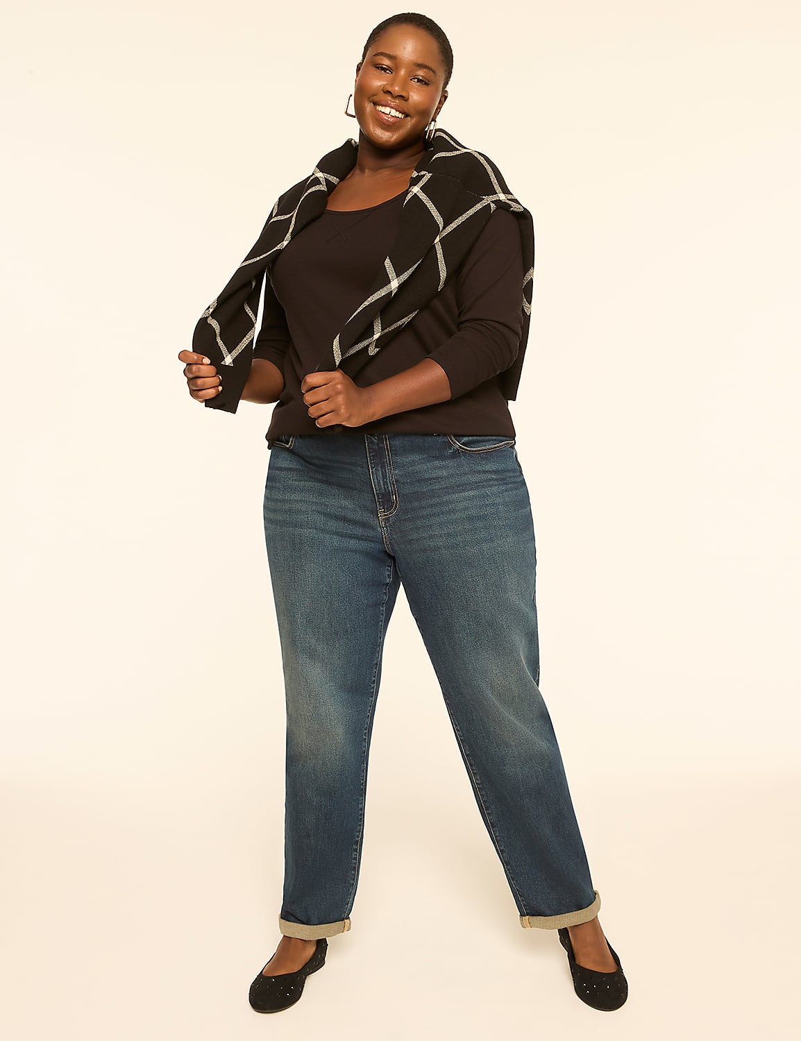 A smiling woman in jeans and a sweater stands against a plain, light-colored background. Product Image 3