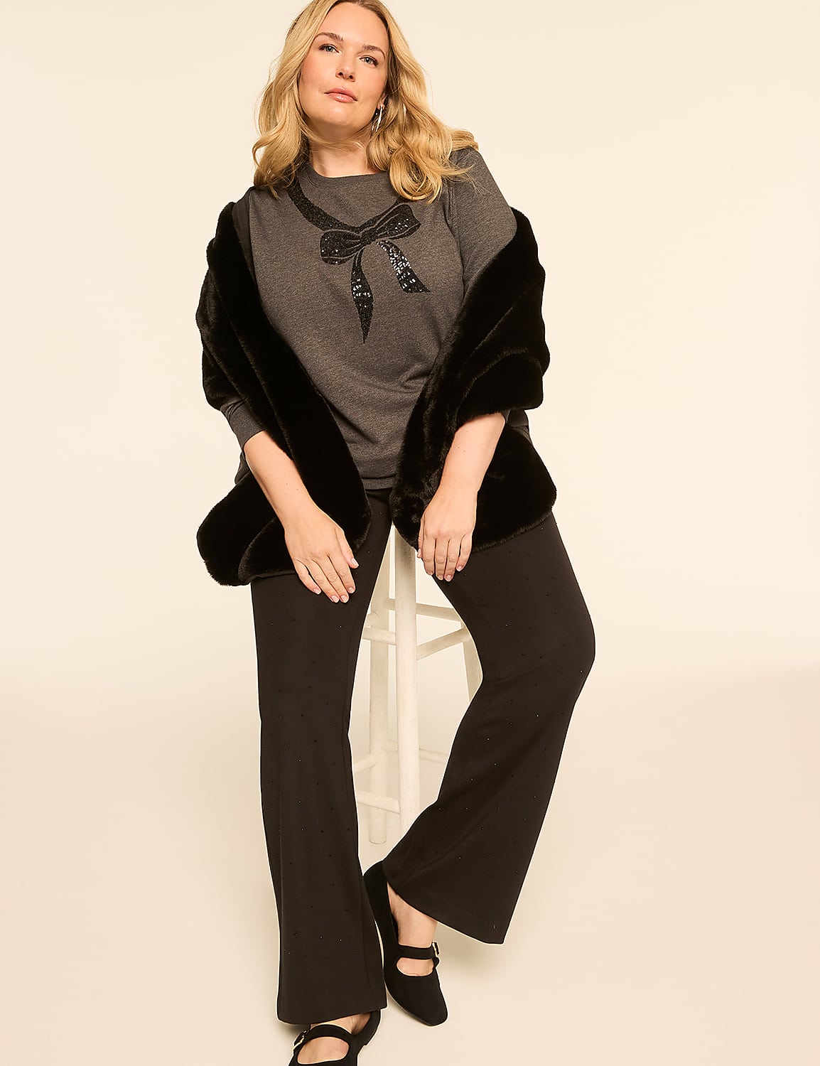 A woman in a gray top and black pants sits on a stool, draped in a black faux fur stole, against a plain, light-colored background. Product Image 3