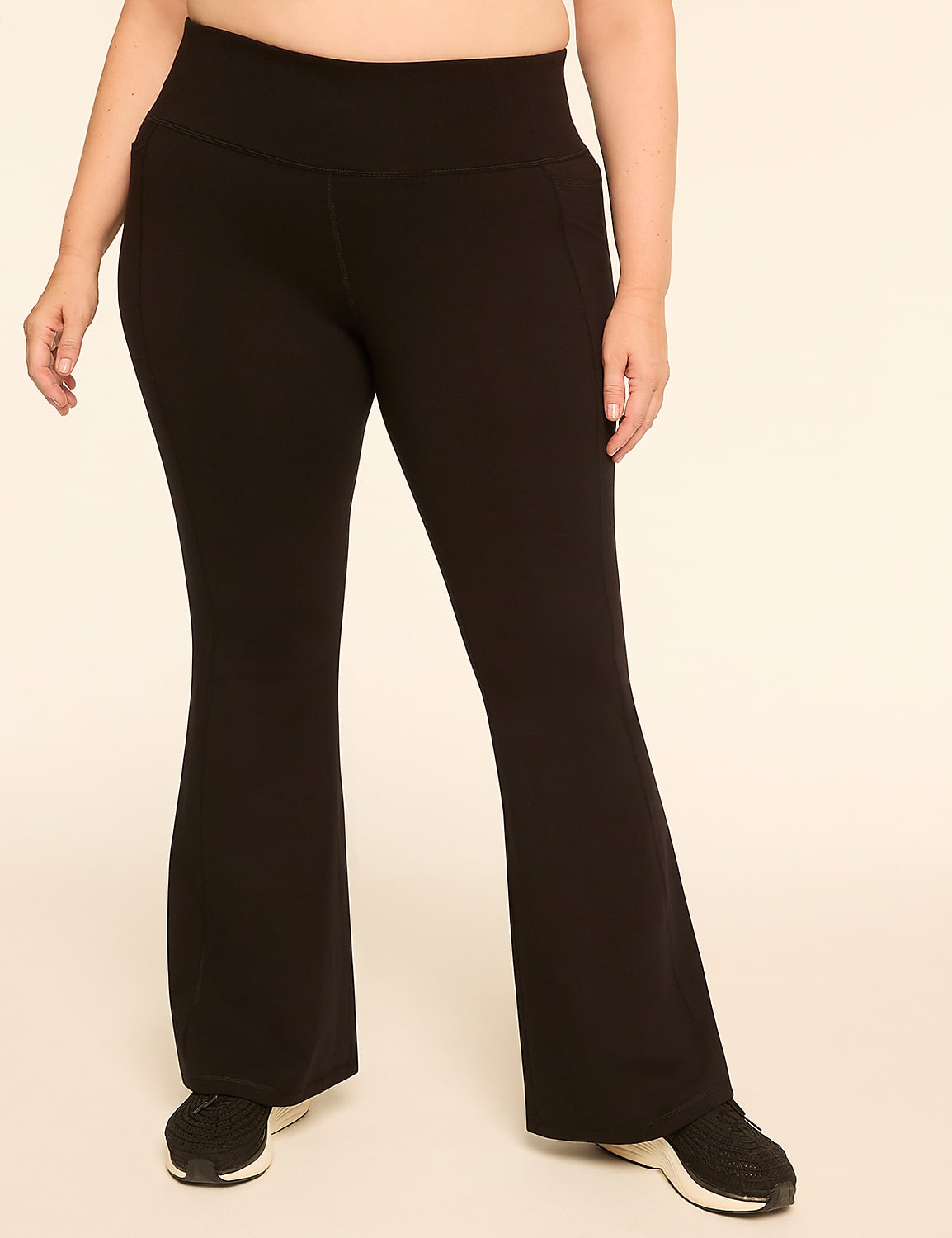 A person wearing black flare yoga pants and sneakers stands against a plain, light-colored background. Product Image 1