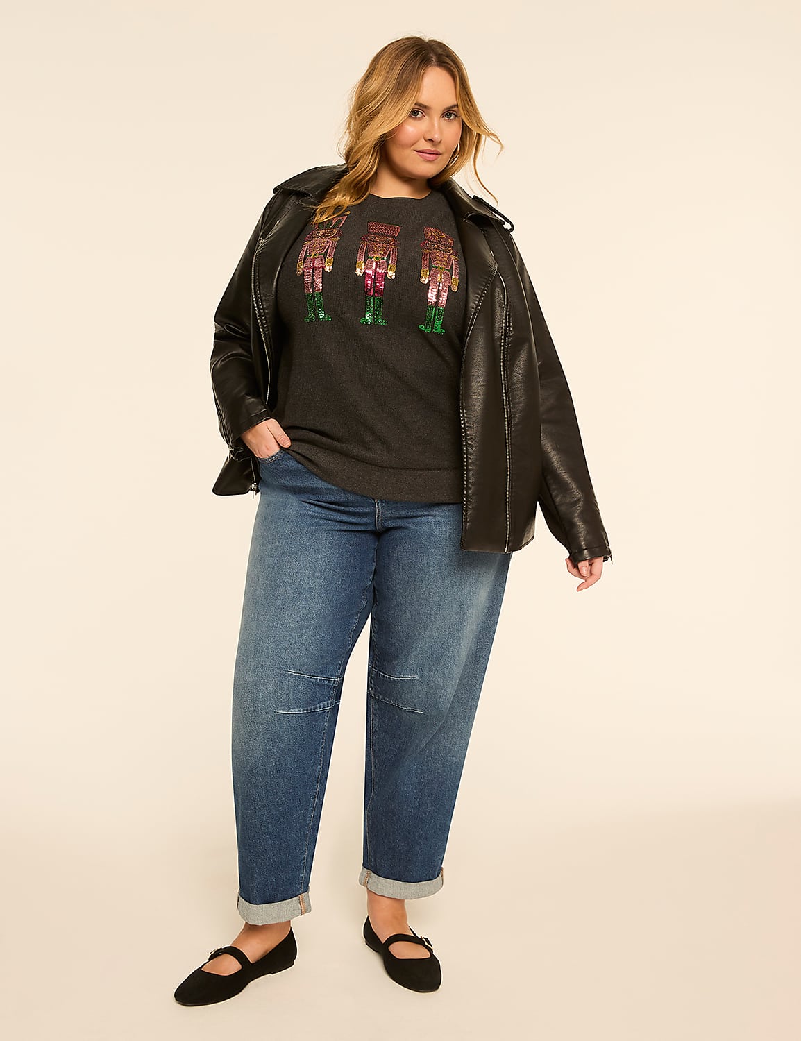 A woman in a black leather jacket, graphic t-shirt, and jeans stands against a plain, light-colored background. Product Image 3