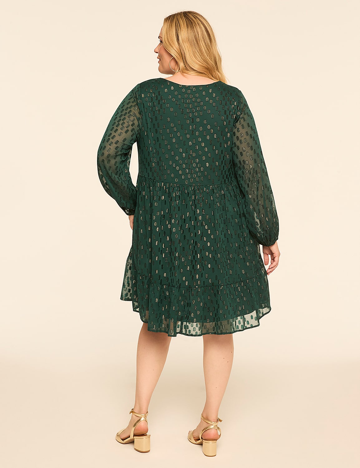 A woman in a green, tiered, long-sleeved dress with a subtle metallic pattern stands against a plain, light-colored background. Product Image 2