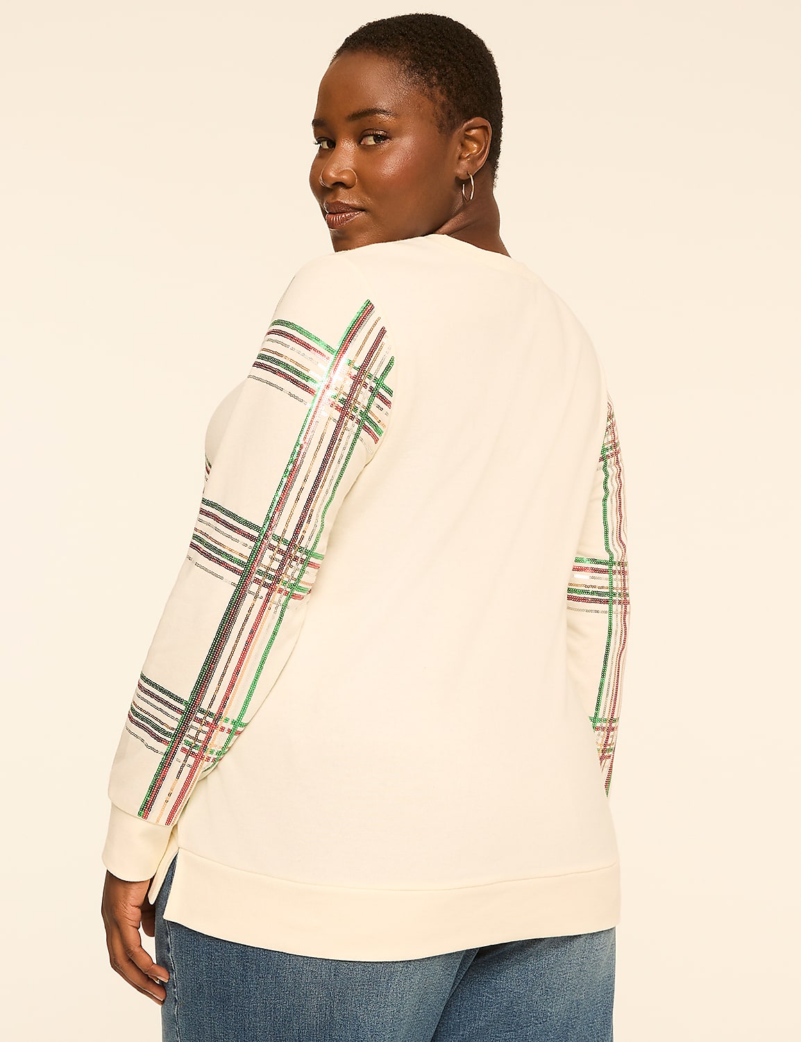 A woman in a cream-colored sweatshirt with plaid sleeves stands against a plain, light-colored background. Product Image 2