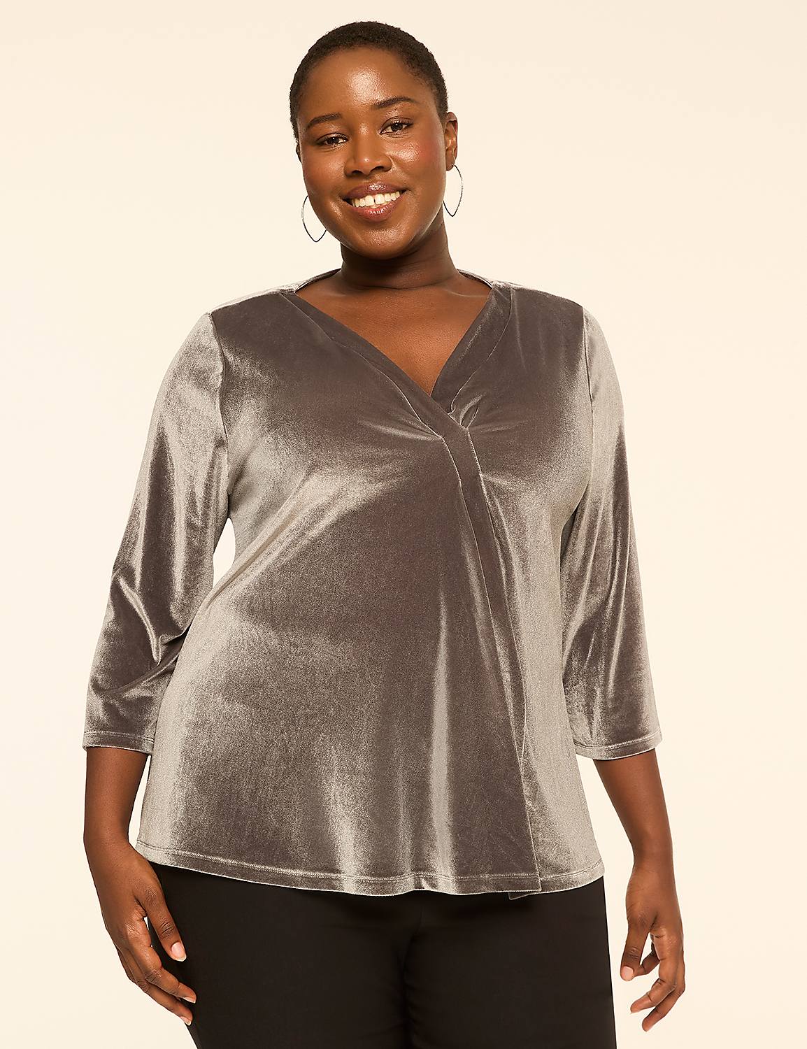 A smiling woman in a silver velvet top stands against a plain, light-colored background. Product Image 1