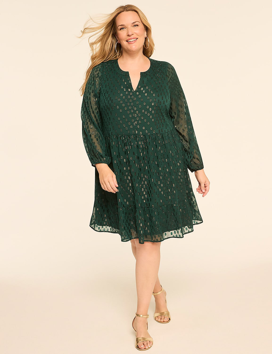 A smiling woman in a green patterned dress stands against a plain, light-colored background. Product Image 1