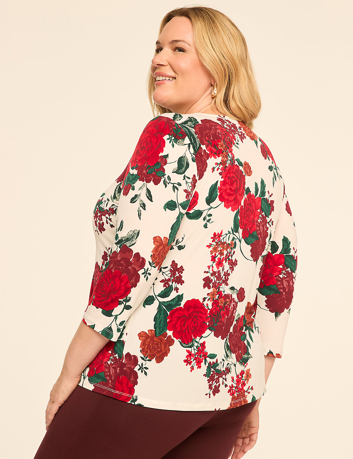 A woman in a floral top and maroon pants smiles over her shoulder against a plain background. Product Image 2