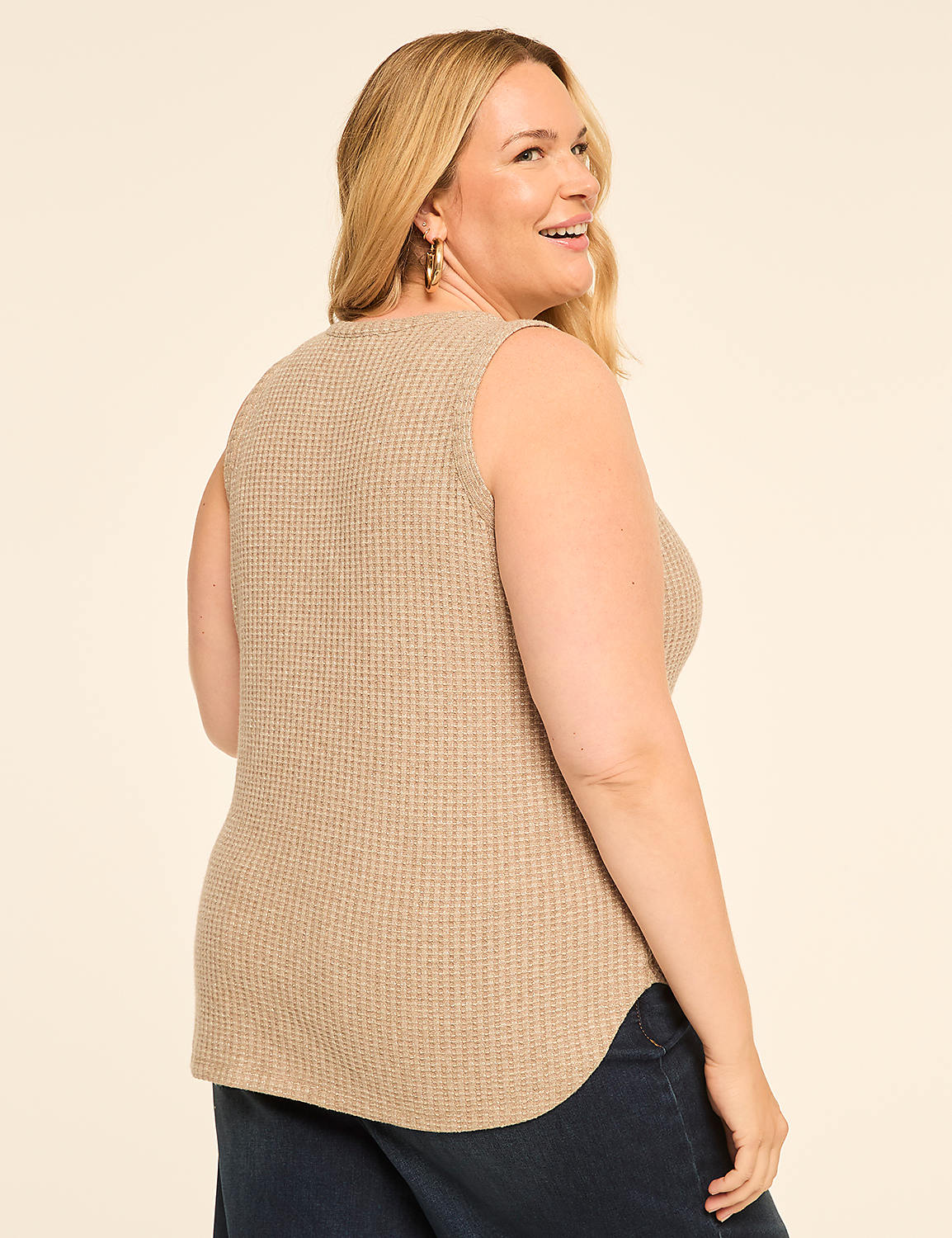 A woman in a beige waffle-knit tank top and dark jeans smiles over her shoulder against a plain, light-colored background. Product Image 2