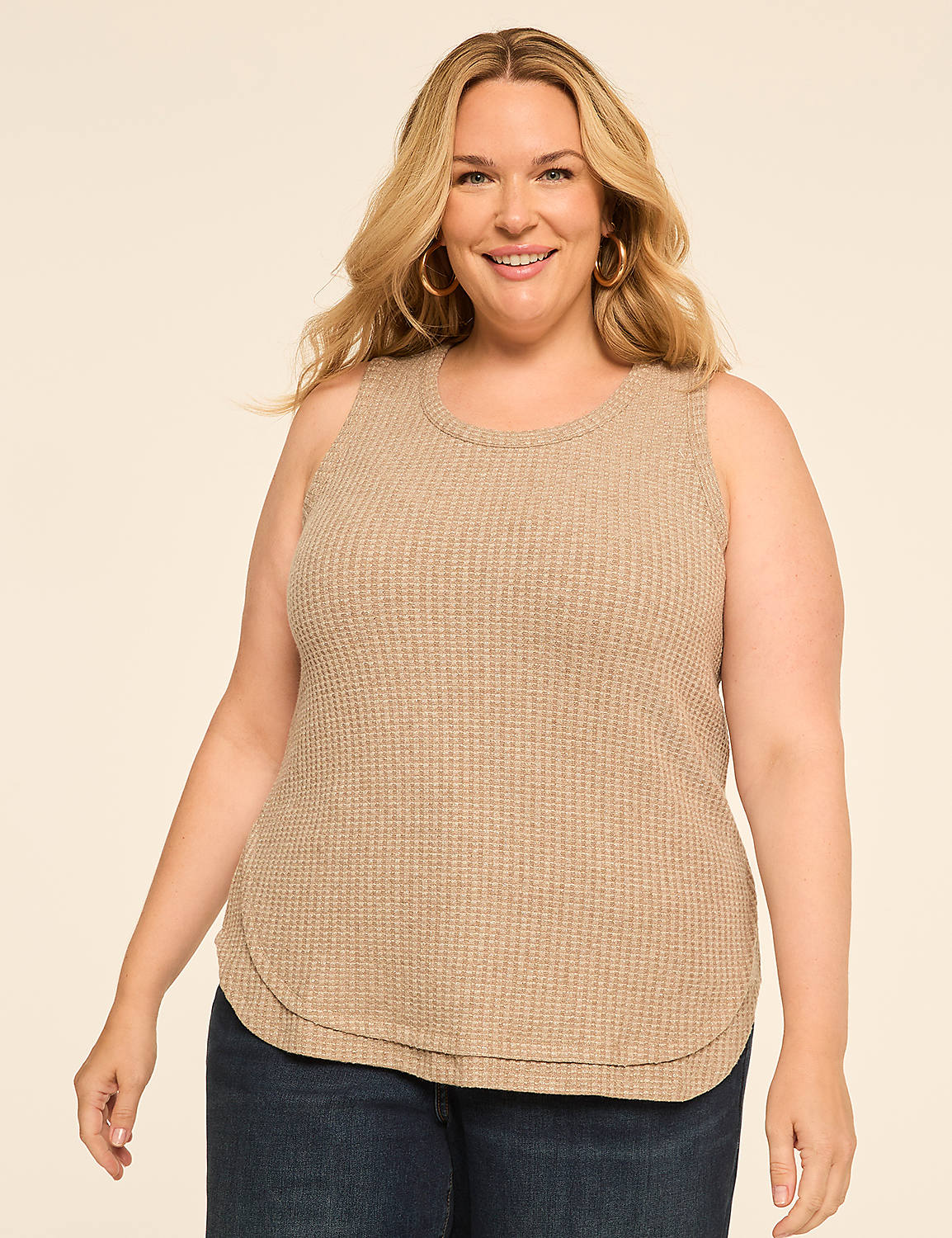 A smiling woman with blonde hair and hoop earrings poses in a tan waffle-knit tank top and blue jeans against a plain, light-colored background. Product Image 1