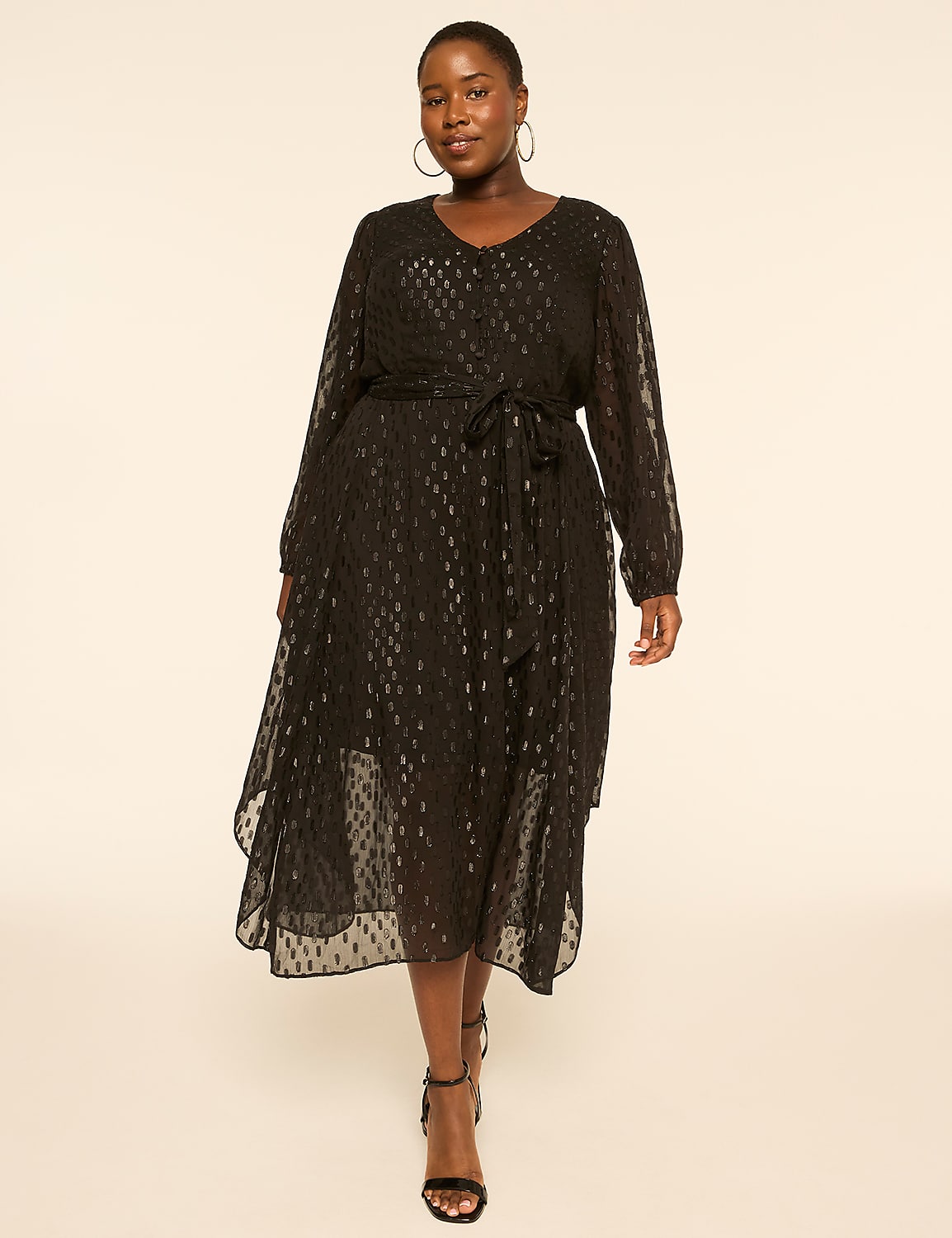 A woman in a black patterned dress stands against a plain, light-colored background. Product Image 1