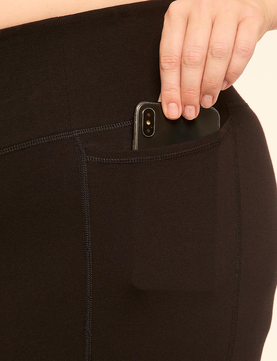 A hand places a smartphone into the pocket of black leggings against a plain background. Product Image 4
