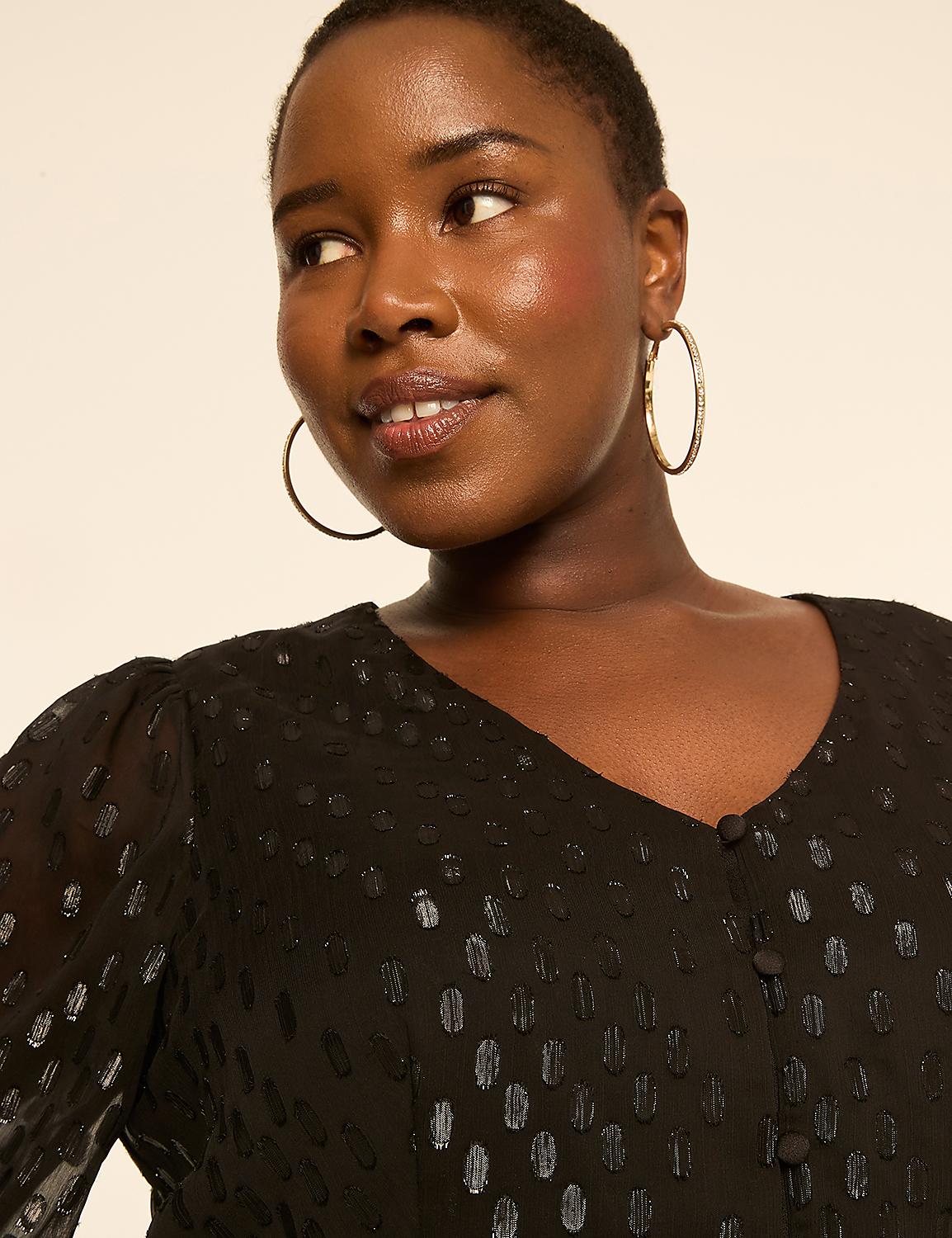 A woman with short hair and large hoop earrings smiles slightly in a black, textured dress against a plain, light-colored background. Product Image 3