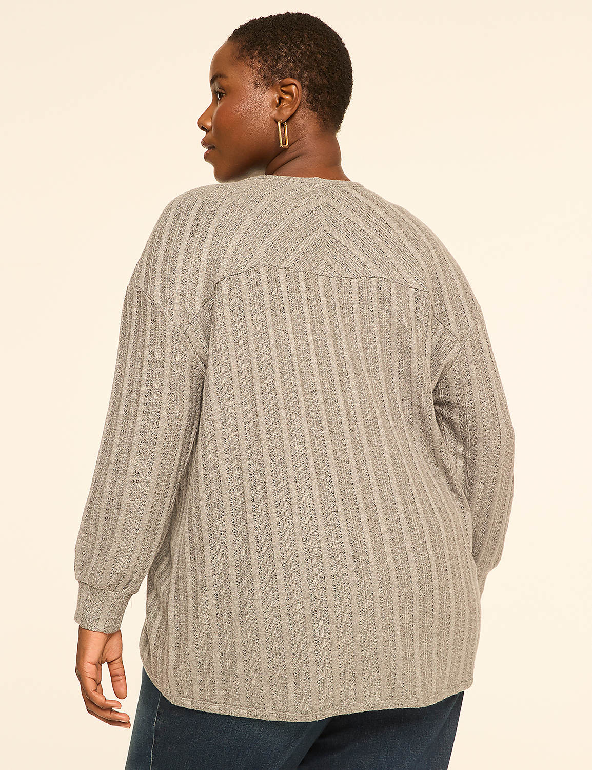 A woman in a grey textured sweater stands against a plain cream background. Product Image 2