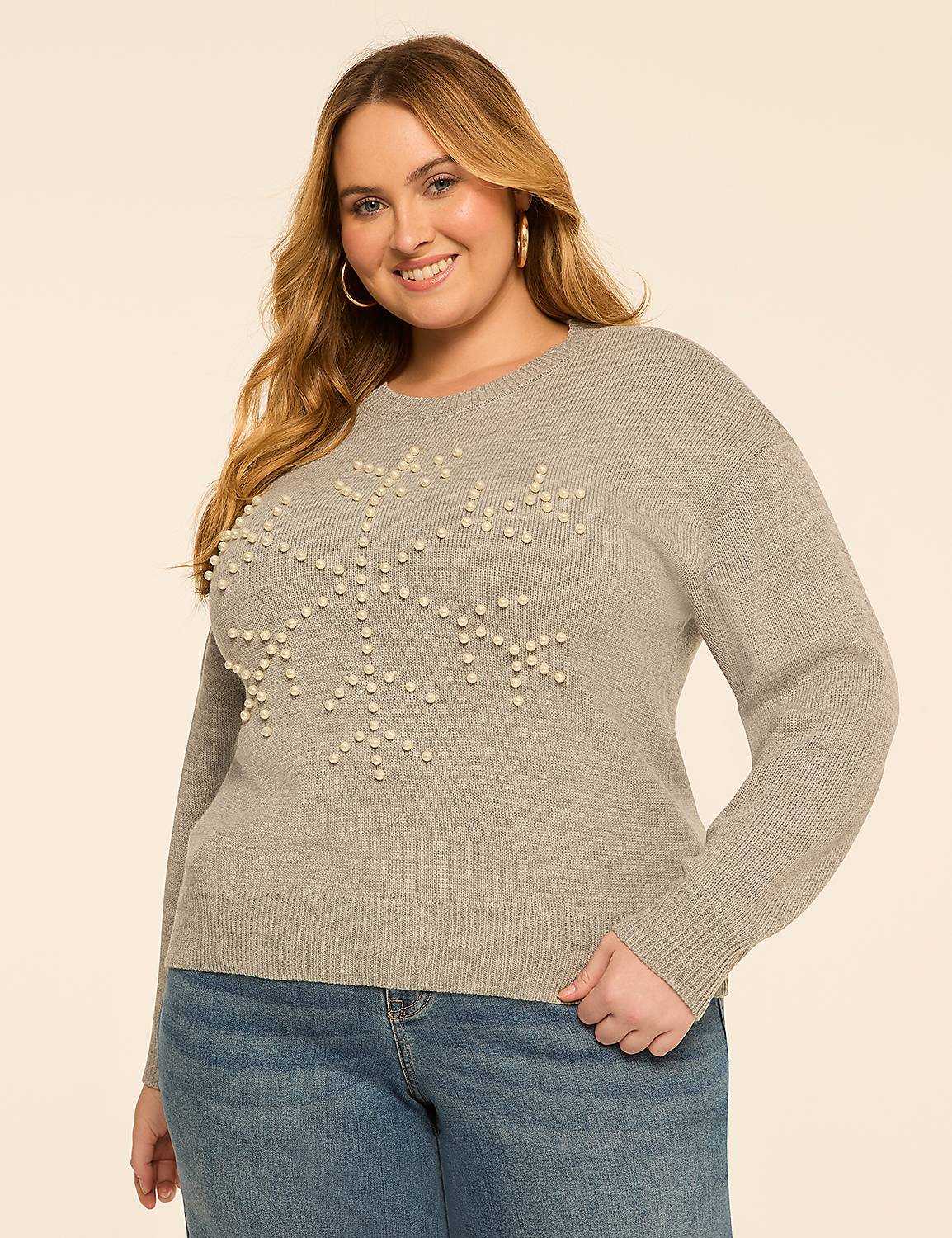 A smiling woman in a pearl-adorned snowflake sweater and jeans stands against a plain, light-colored background. Product Image 1