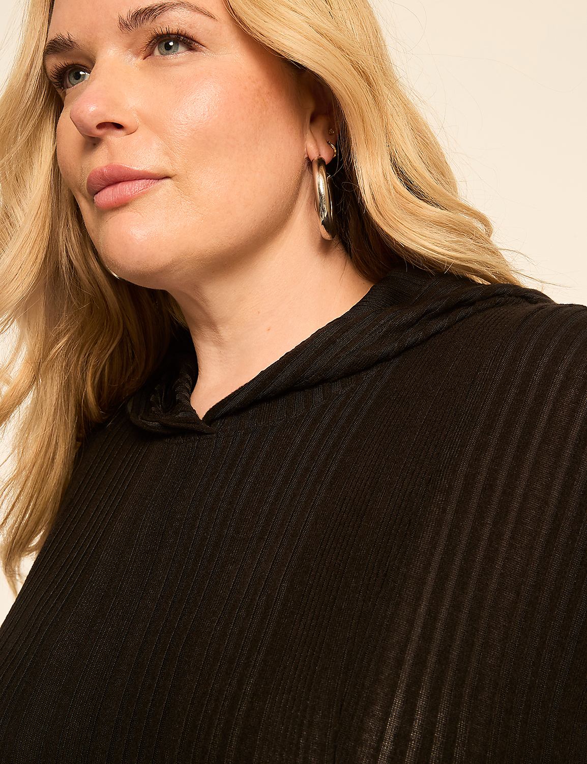 A blonde woman with hoop earrings wears a black hooded top against a plain, light-colored background. Product Image 4