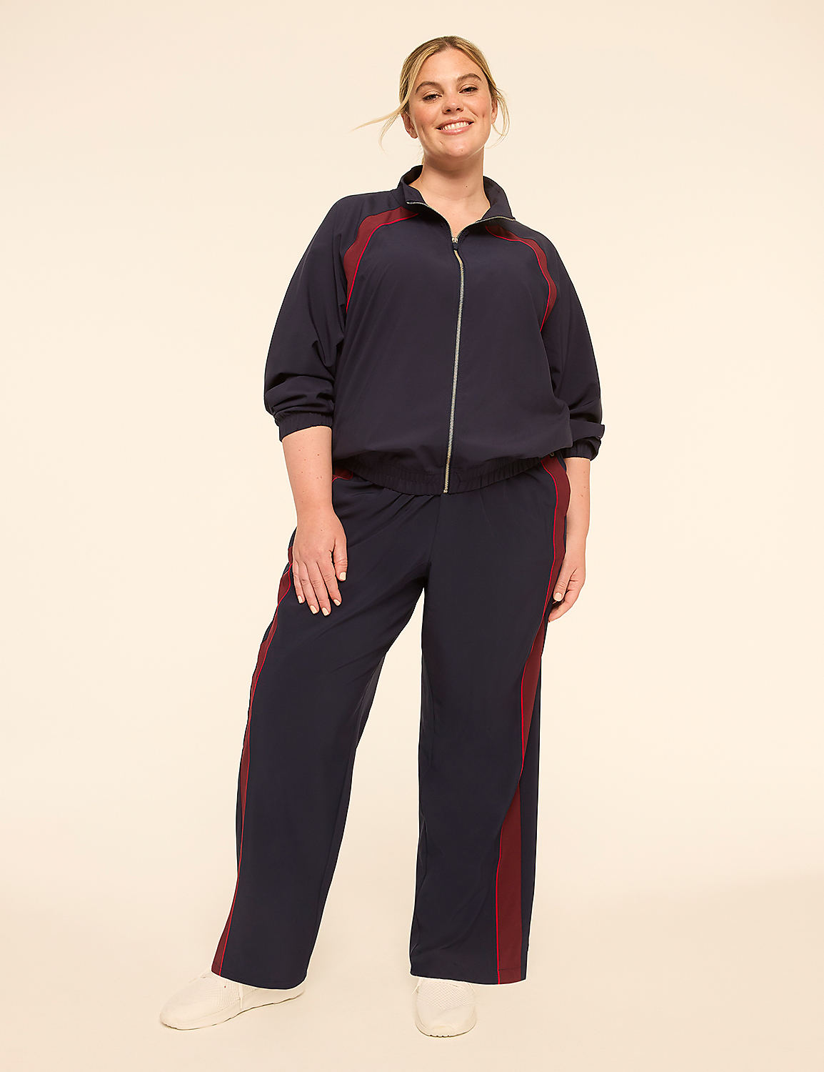 A smiling woman in a navy tracksuit with maroon stripes stands against a plain, light-colored background. Product Image 3