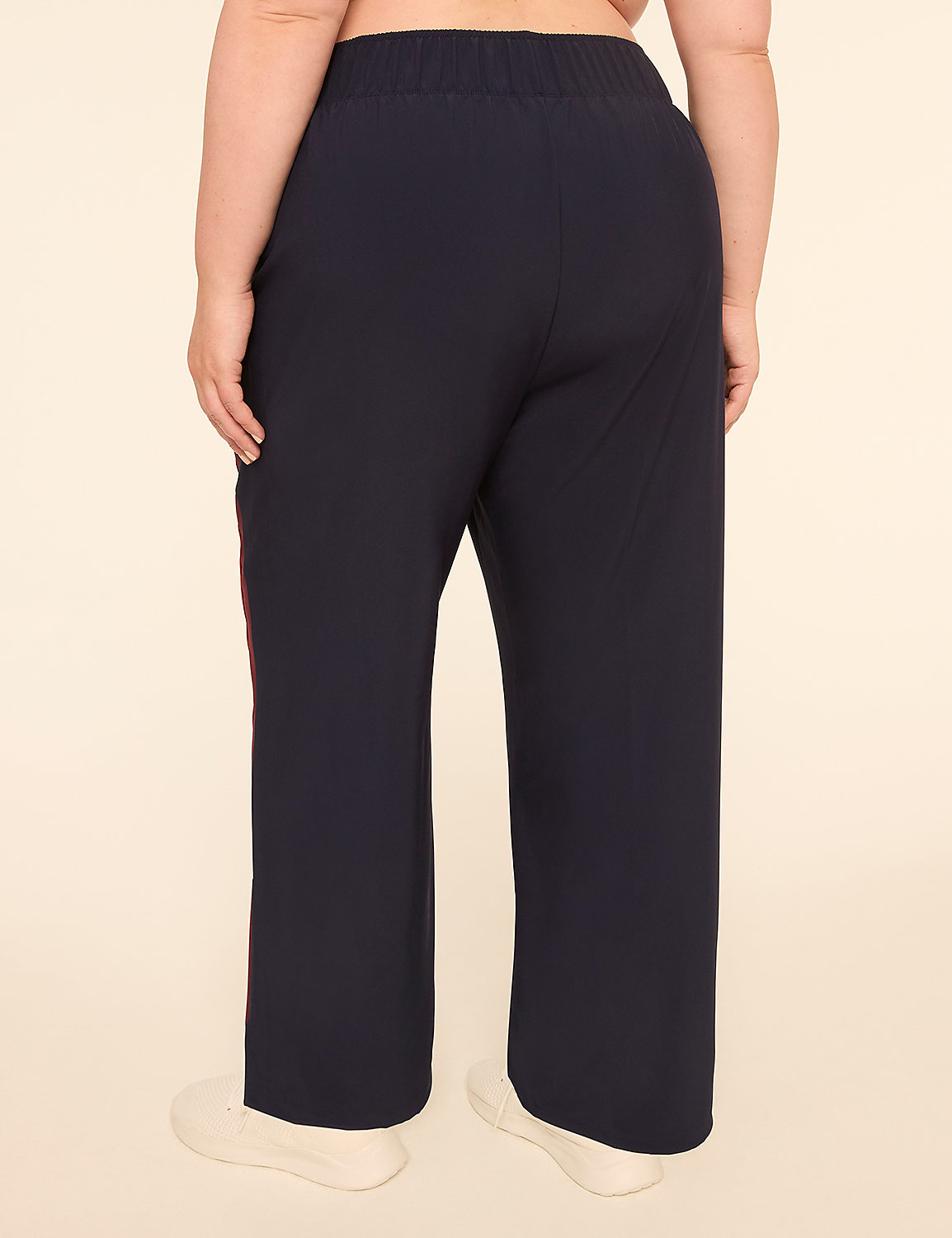 A person wearing dark blue pants with a red stripe down the side stands against a plain, light-colored background. Product Image 2