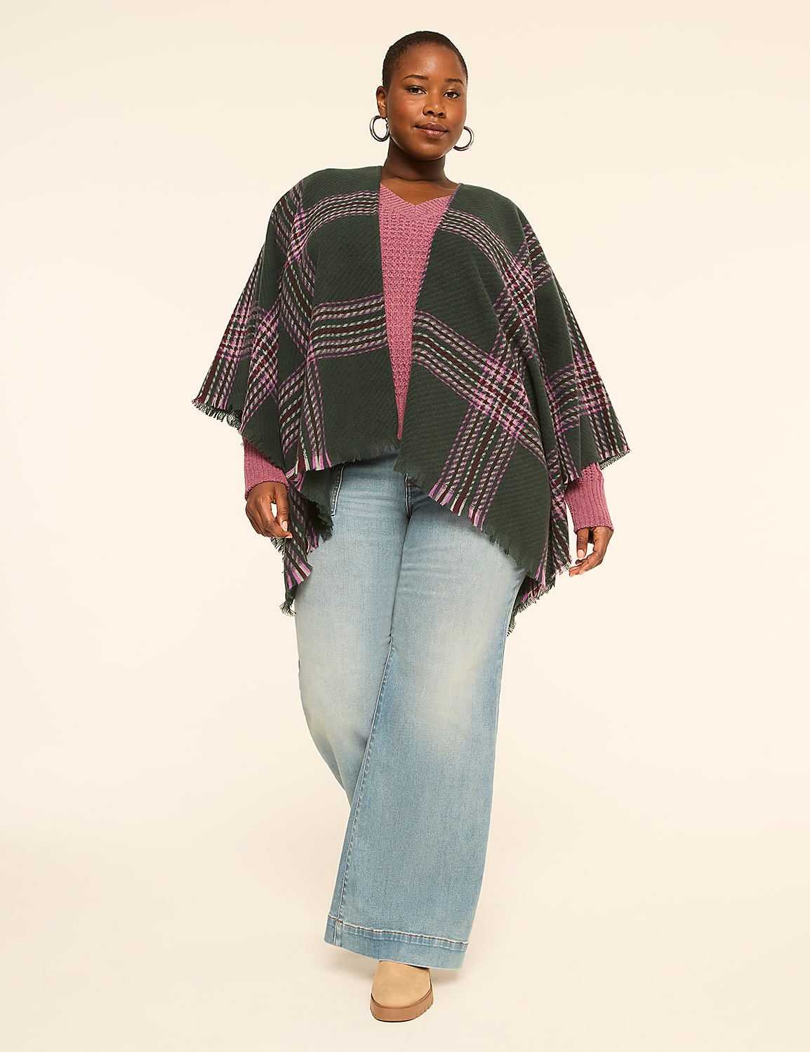 A woman in a green plaid poncho and pink sweater stands in front of a plain, light-colored background. Product Image 3