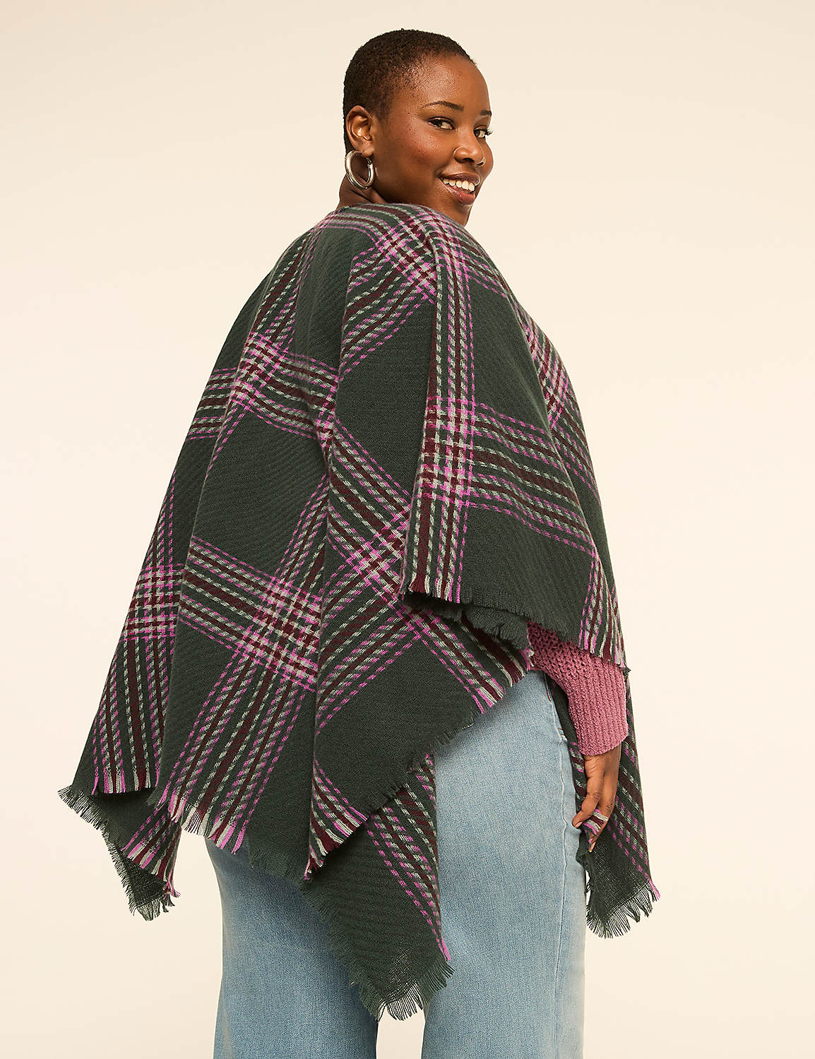 A woman in a green and purple plaid poncho and pink sweater smiles over her shoulder against a plain, light background. Product Image 2