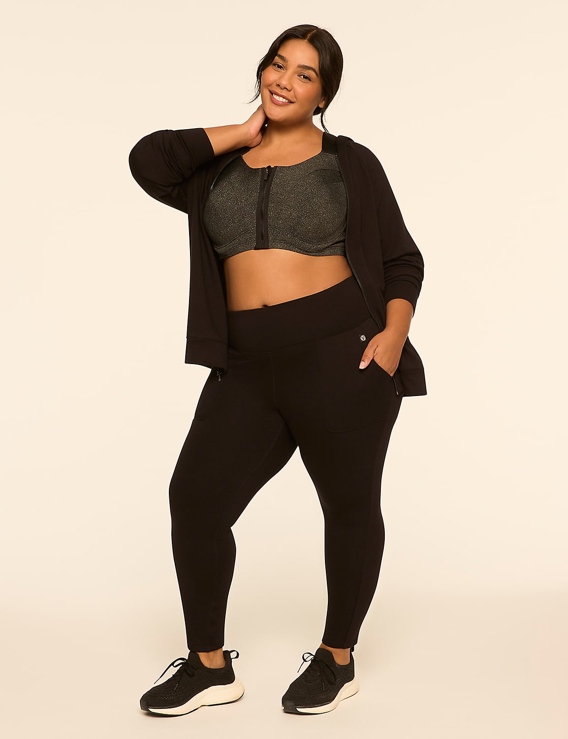 A smiling woman in athletic wear stands against a plain, light-colored background. Product Image 3