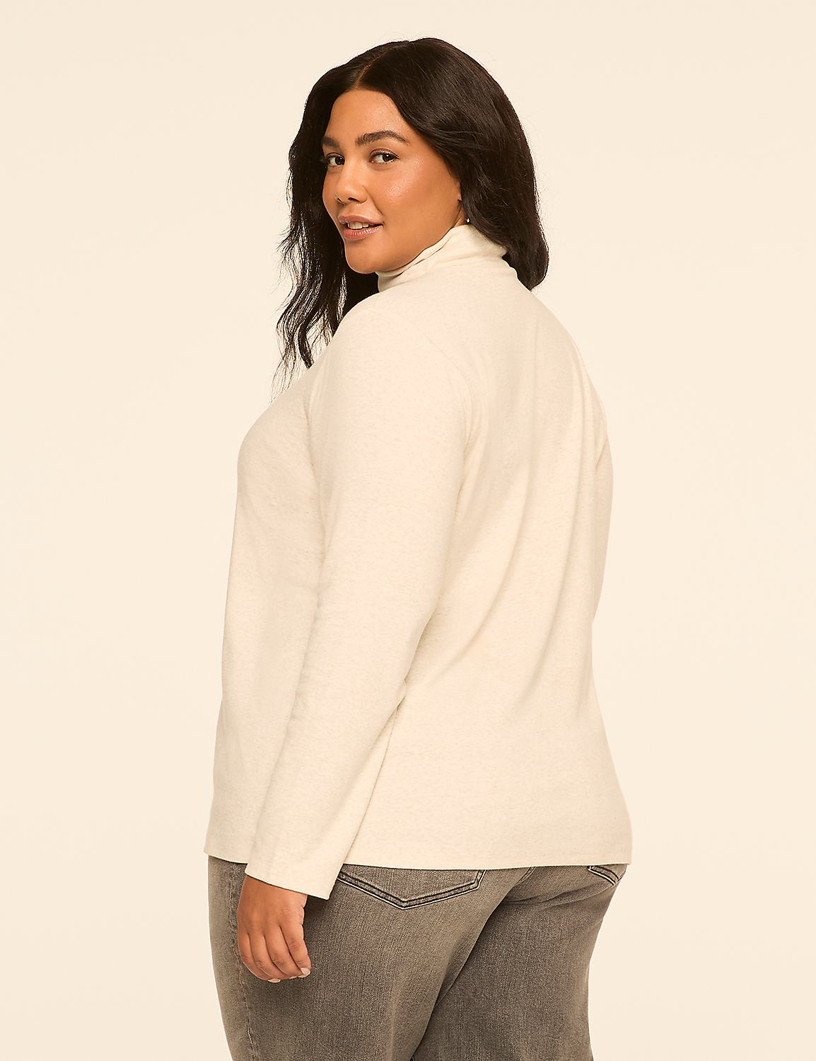 A woman in a cream turtleneck and gray jeans stands against a plain, light beige background. Product Image 2