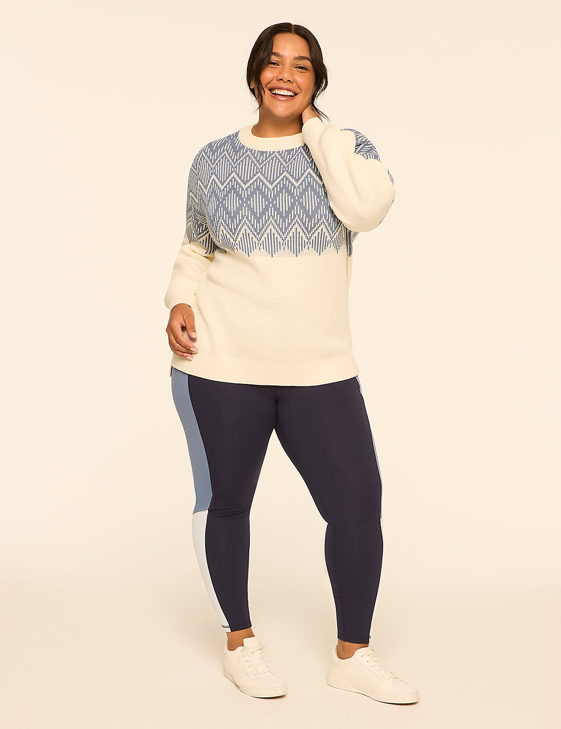 A smiling woman in a cream and blue patterned sweater and navy leggings stands against a plain, light-colored background. Product Image 3