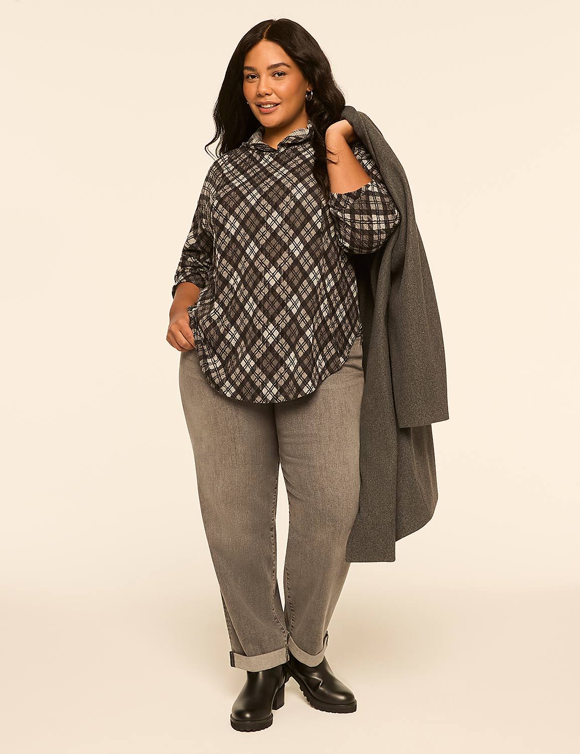 A woman in a plaid shirt and gray pants stands against a plain, light-colored background, with a gray coat draped over her shoulder. Product Image 3