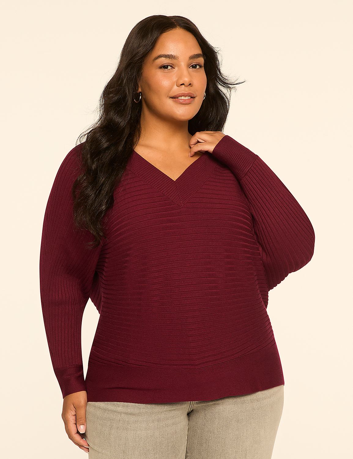 A woman in a maroon v-neck sweater and grey pants stands against a plain, light-colored background. Product Image 1