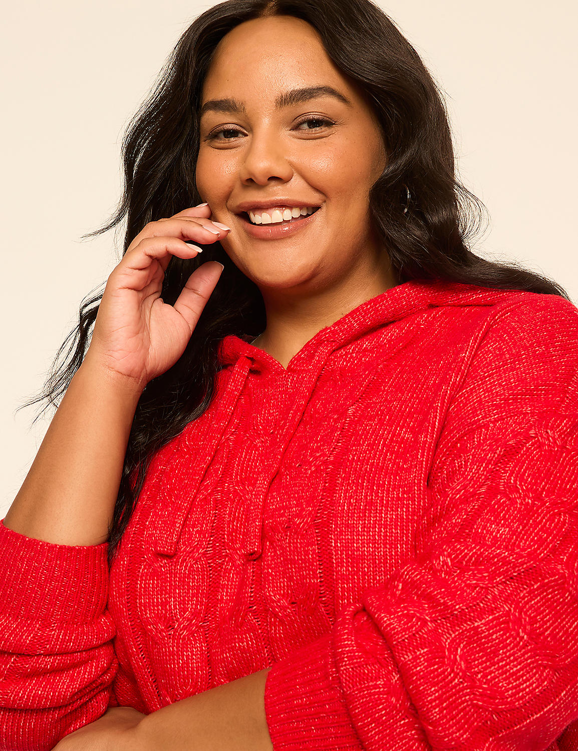 A smiling woman in a red cable-knit hoodie is captured against a plain, light-colored background. Product Image 4