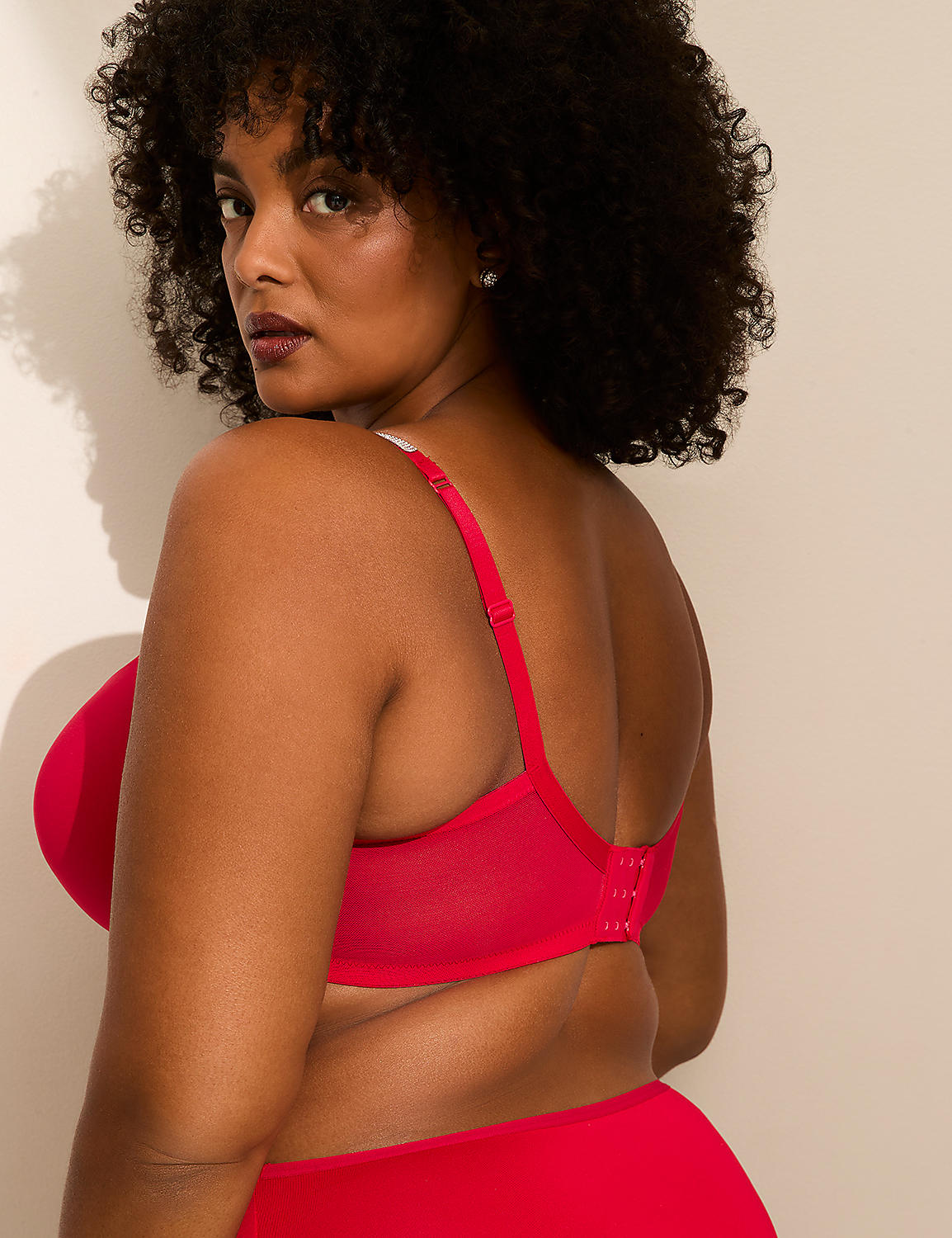 A woman with dark curly hair and a red bra is shown from the side against a plain, light-colored background. Product Image 3
